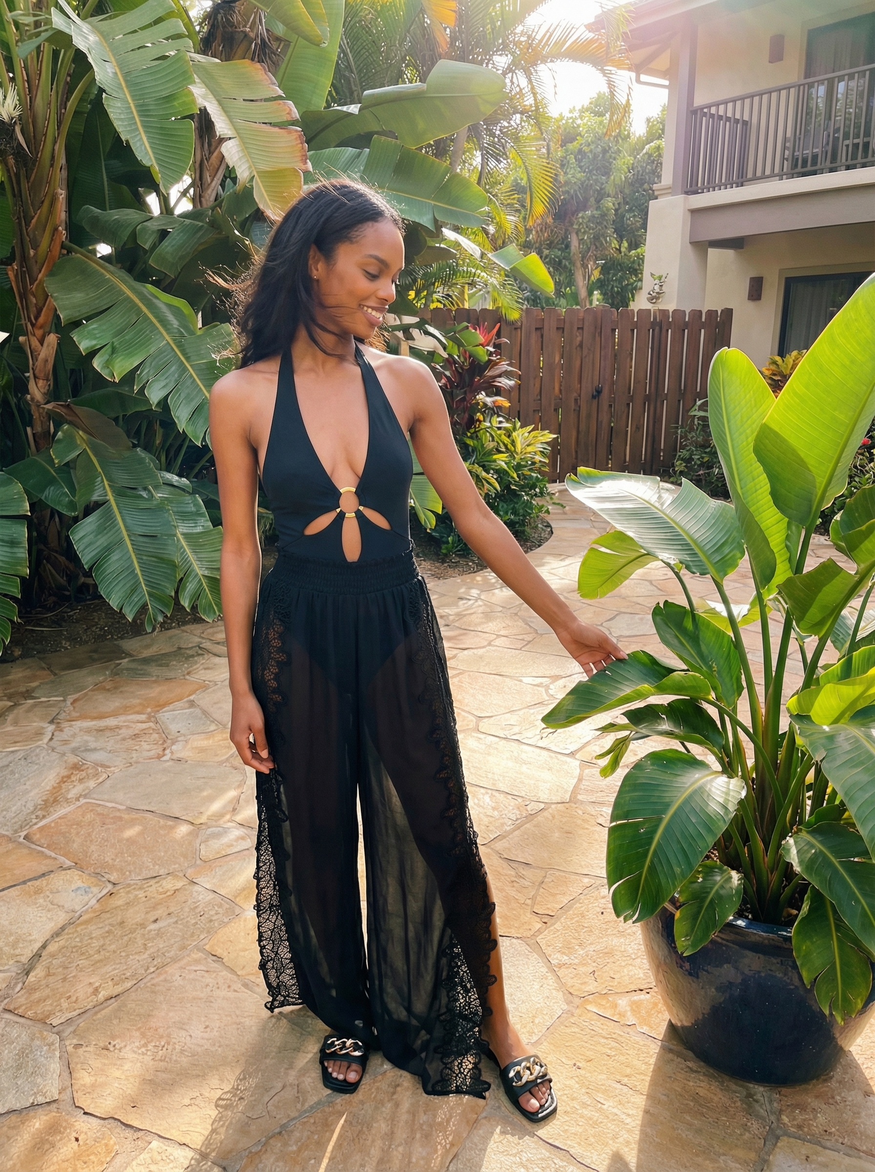 Glamorous poolside baddie summer outfit featuring a black one-piece swimsuit, sheer black wide-leg cover-up pants, and gold accents. Perfect for a beach club or resort.