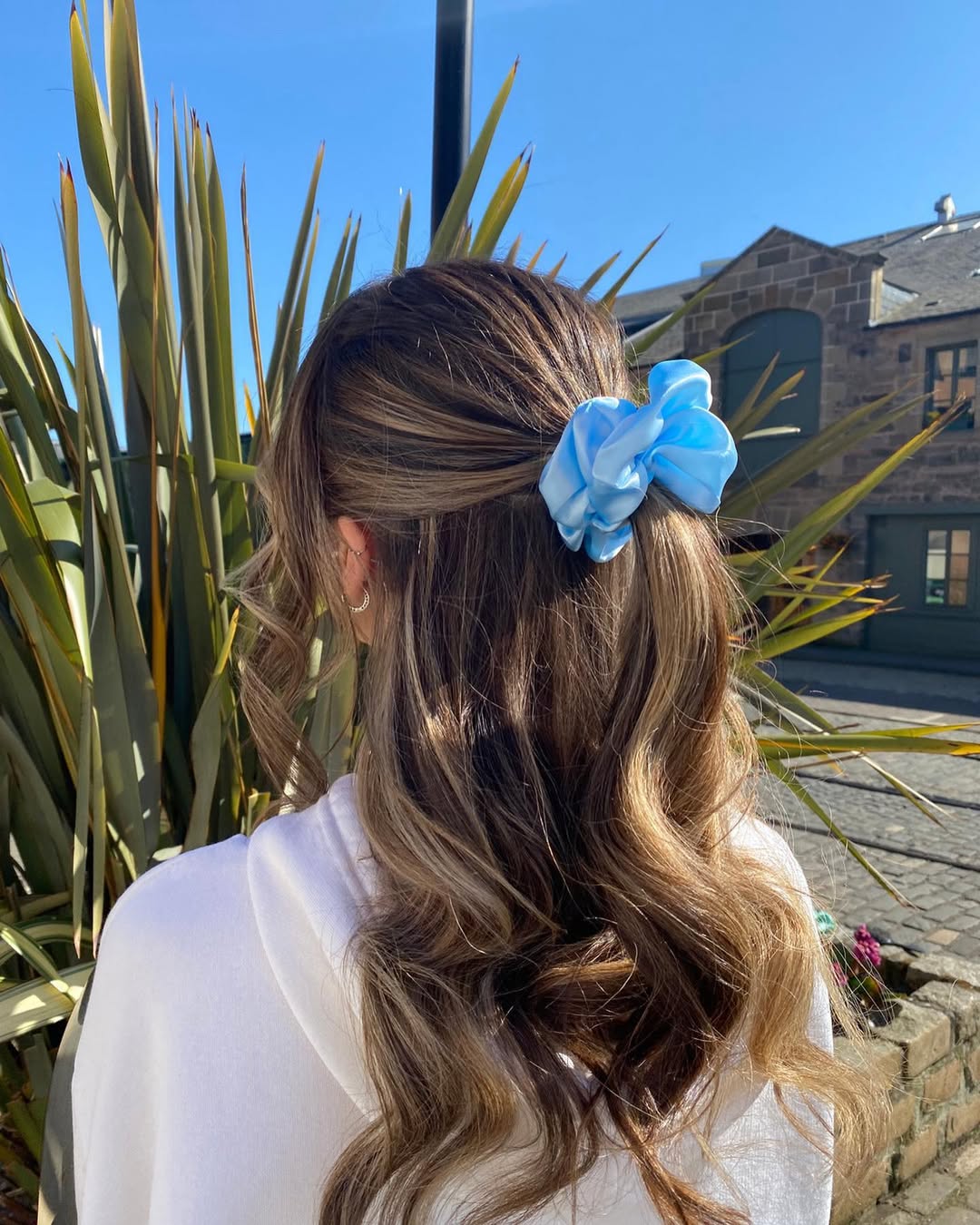 Close-up of a woman with long, sun-kissed blonde hair styled in soft, beachy waves, perfect for cool summer hair ideas. Her hair exudes effortless texture and a natural, carefree vibe, ideal for warm weather.