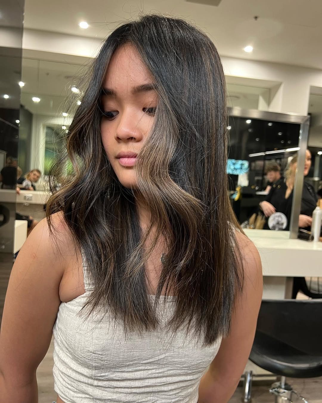 Close-up of a woman with long, rich espresso dark summer hair, styled in loose, beachy waves, perfect for a chic 2026 look. Her hair glistens, showing dimension.