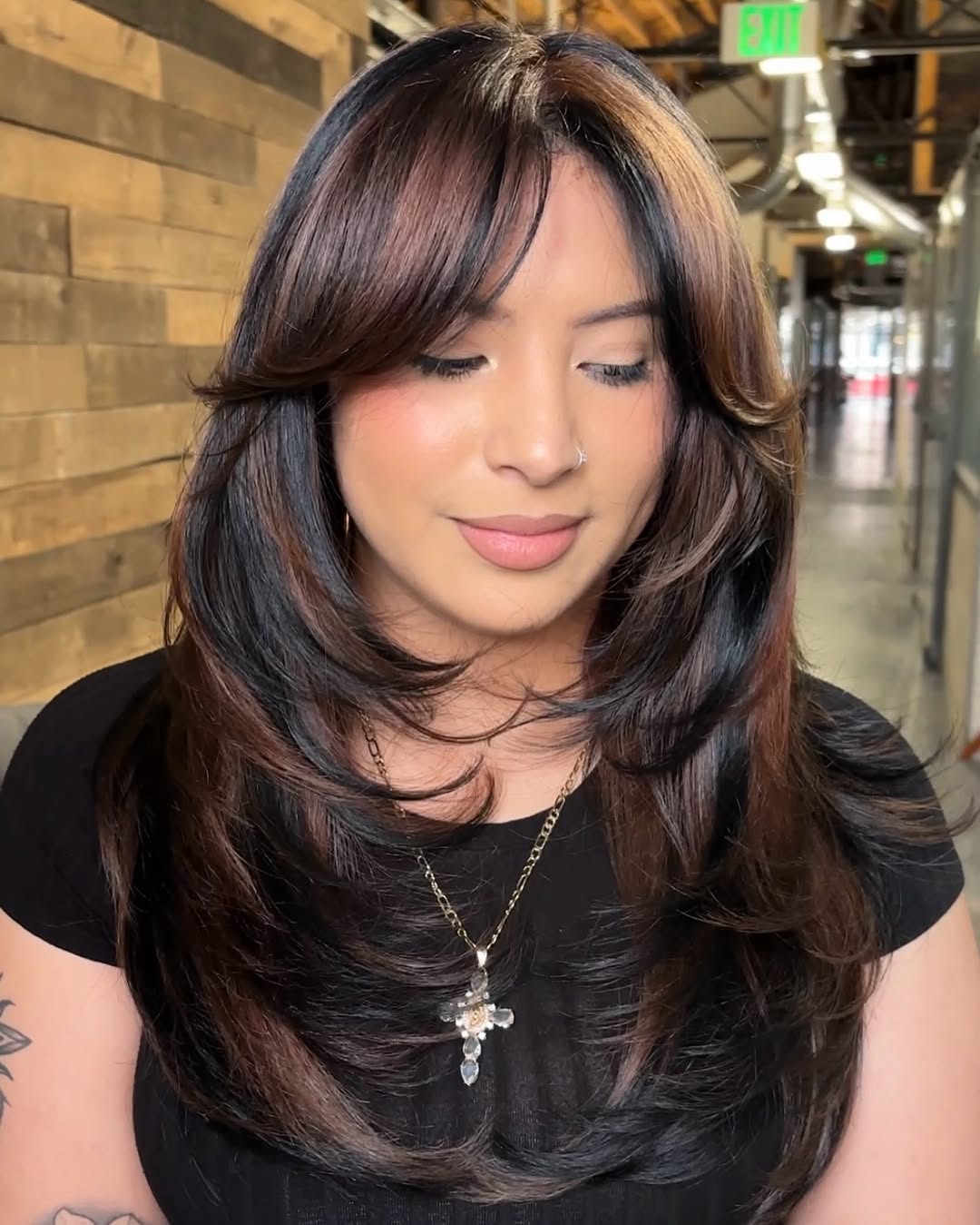 A stunning woman with glossy, dark brown hair styled in soft waves, perfect for dark summer hair ideas 2026. Her hair has subtle auburn undertones, framing her face beautifully.