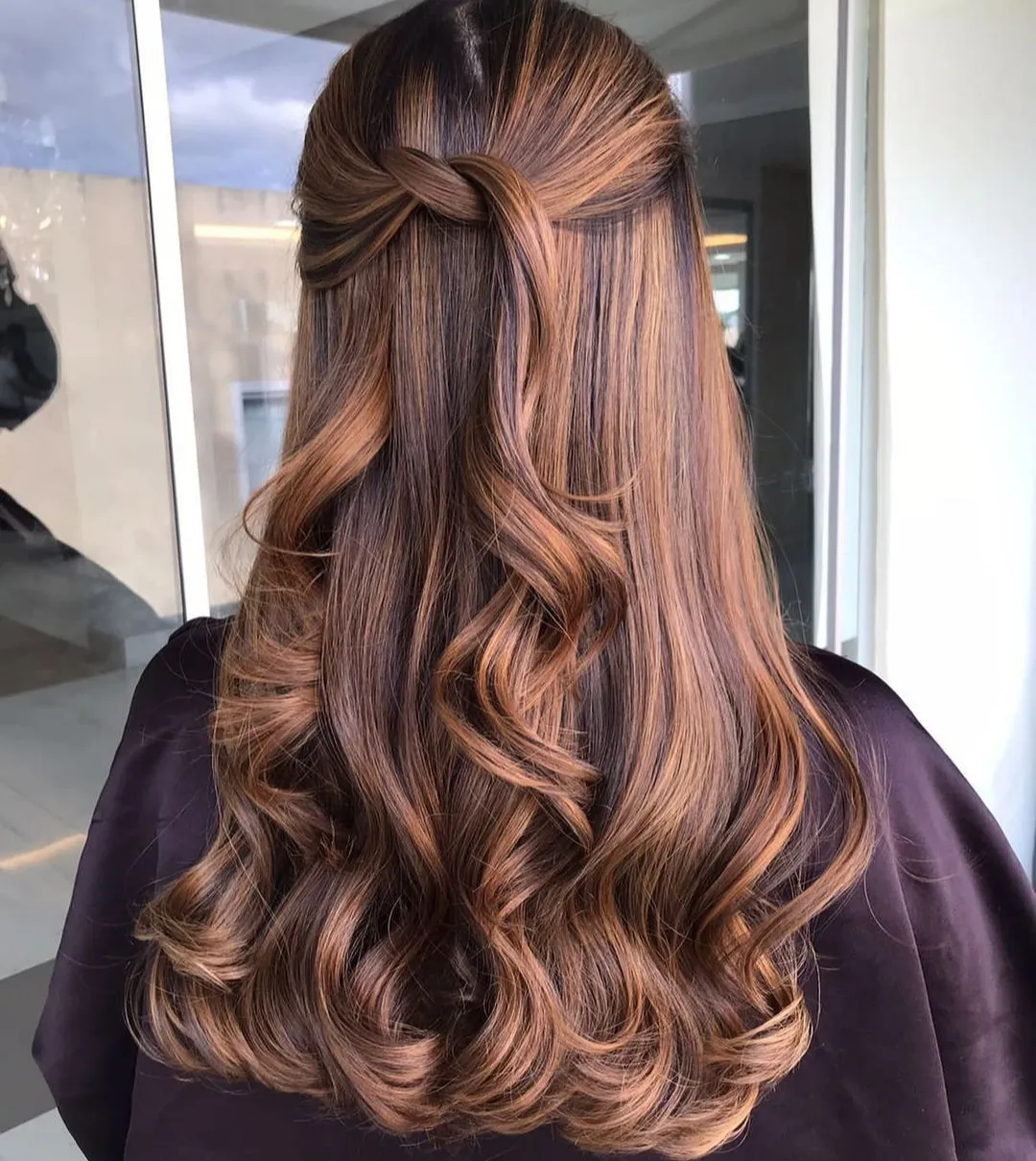 Blonde woman with a braided half-up hairstyle, perfect for easy summer hairstyles 2026. Her hair is curled, and she wears a white floral dress with tie straps, ideal for a garden party.