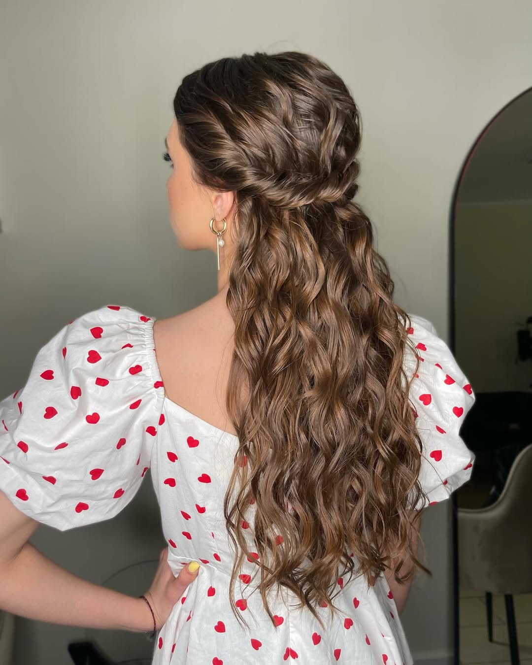 Blonde woman with sun-kissed highlights sporting a half-up messy bun with face-framing tendrils, perfect for easy summer hairstyles 2026. This casual look pairs well with a white crochet top, ideal for beach days or relaxed outings.