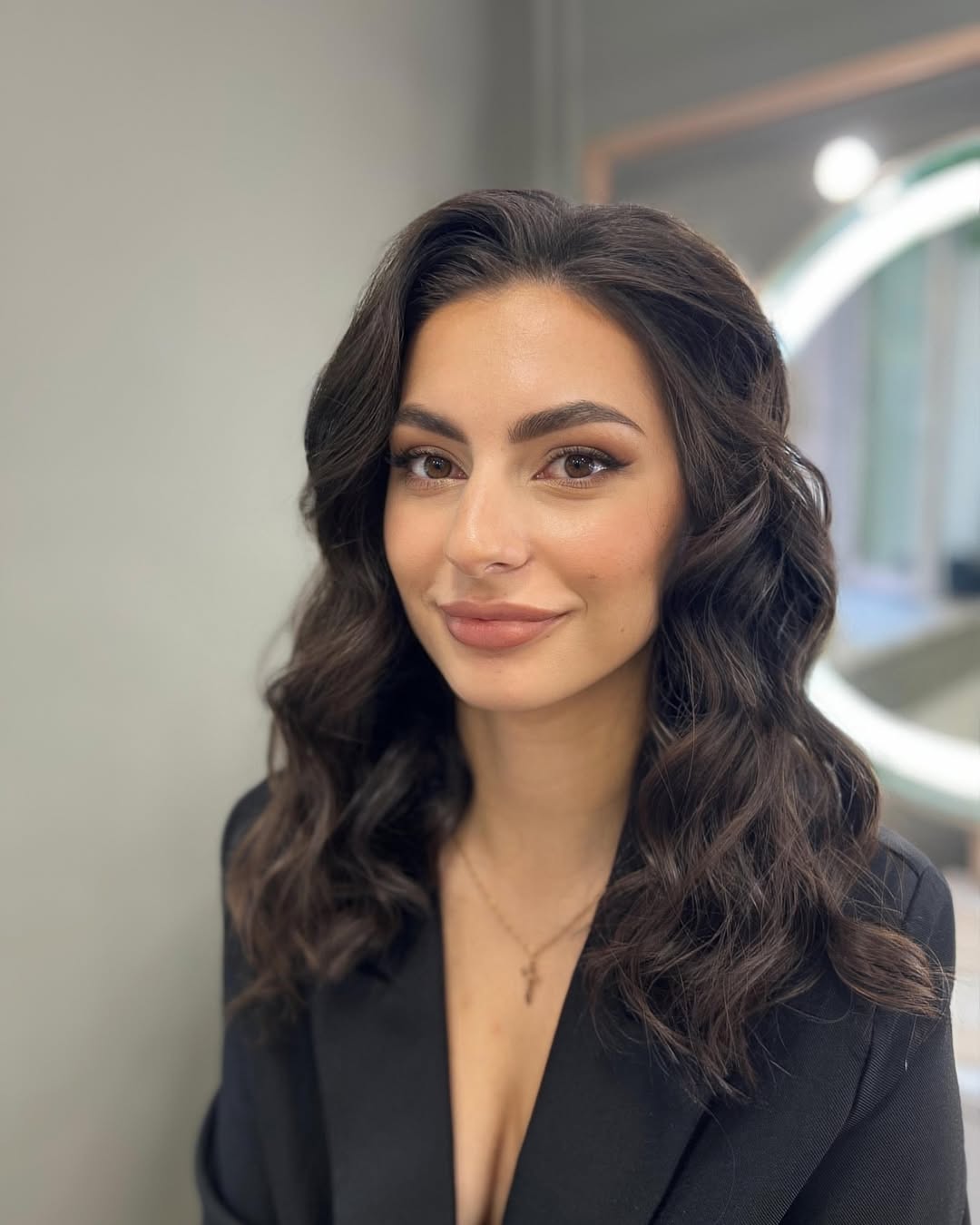 A young woman smiling, demonstrating an easy summer hairstyle for 2026, with sun-kissed highlights in a soft, wavy updo, perfect for a casual day out.