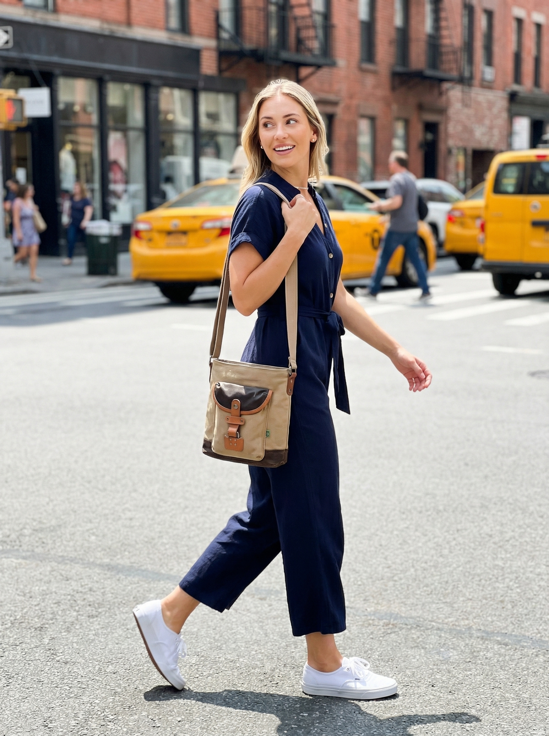 Effortless end of summer outfits for a casual day out: navy utility jumpsuit, white sneakers, tan crossbody bag, gold studs.