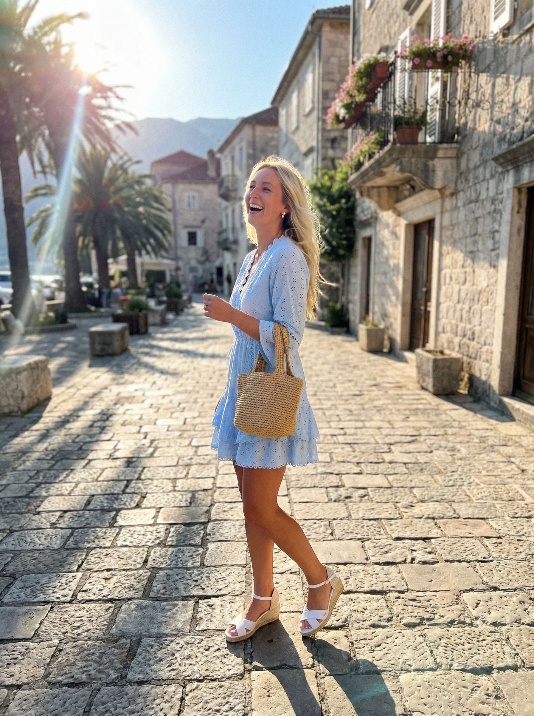 Charming sky blue cotton eyelet mini sundress with white platform espadrille sandals and a straw tote bag, a fresh choice for late summer outfits at a lakeside lunch.