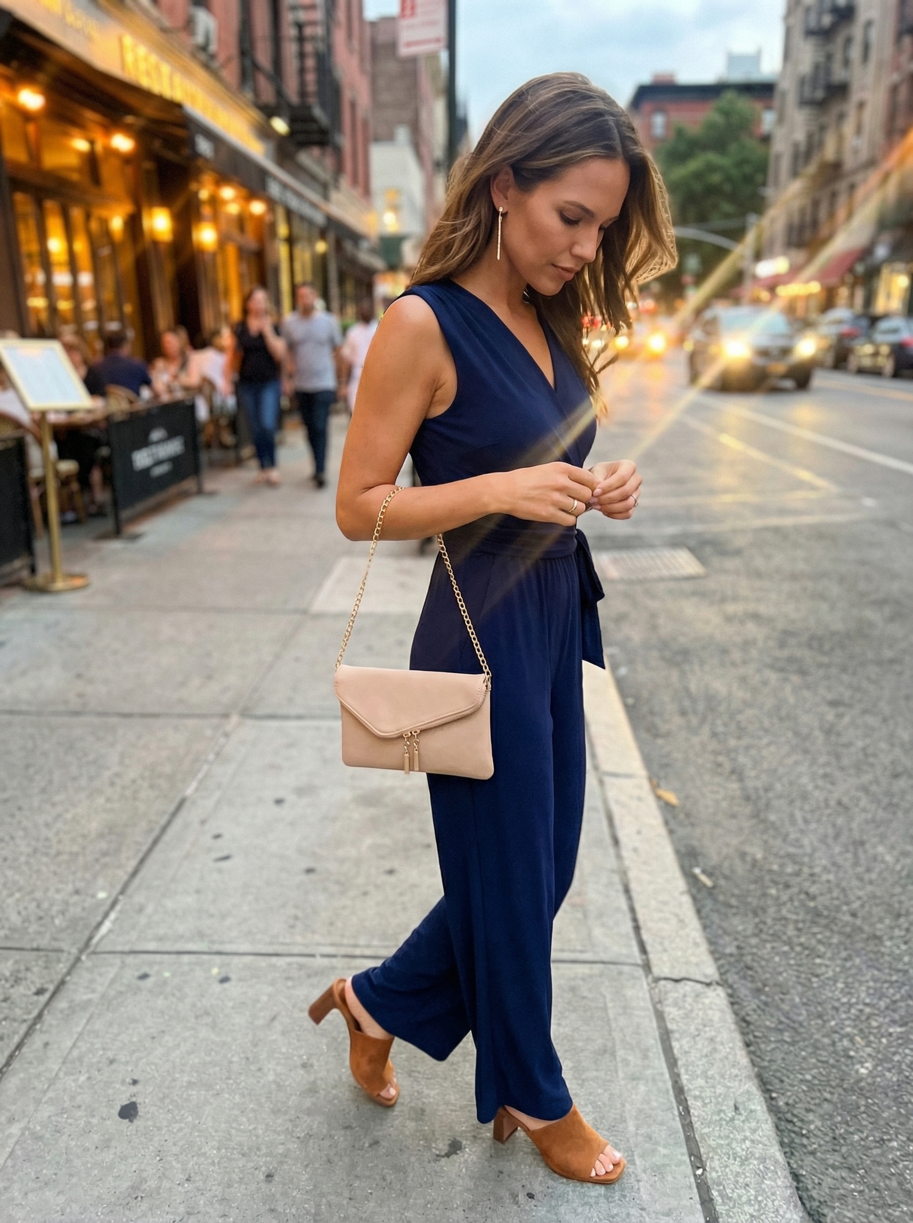 Elegant navy wide-leg sleeveless jumpsuit with nude mules and gold earrings, a modern new york summer outfit for evening events.