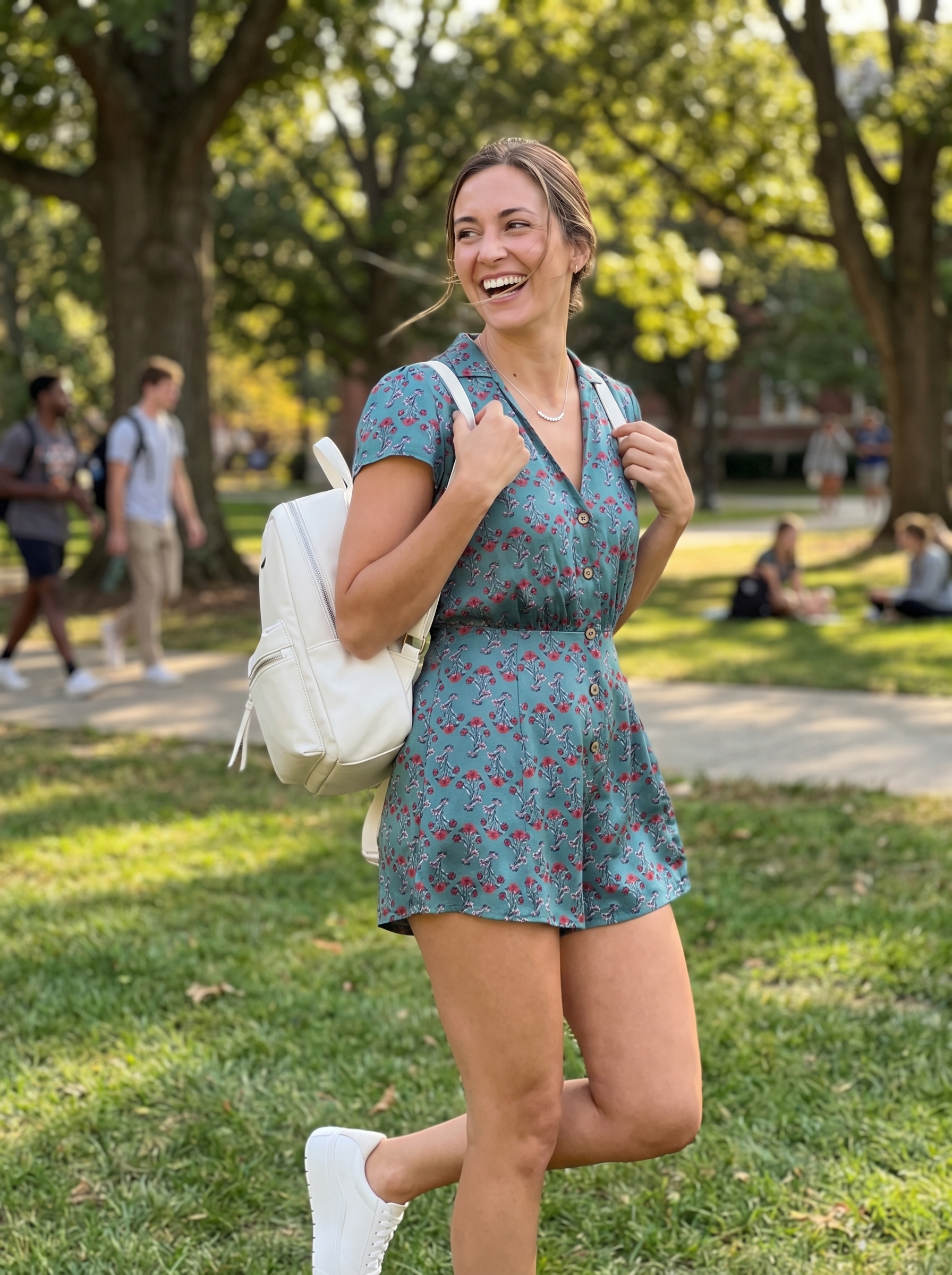 Playful teal floral print romper with white low-top sneakers and a mini backpack, a fun school summer outfit for campus festivities.