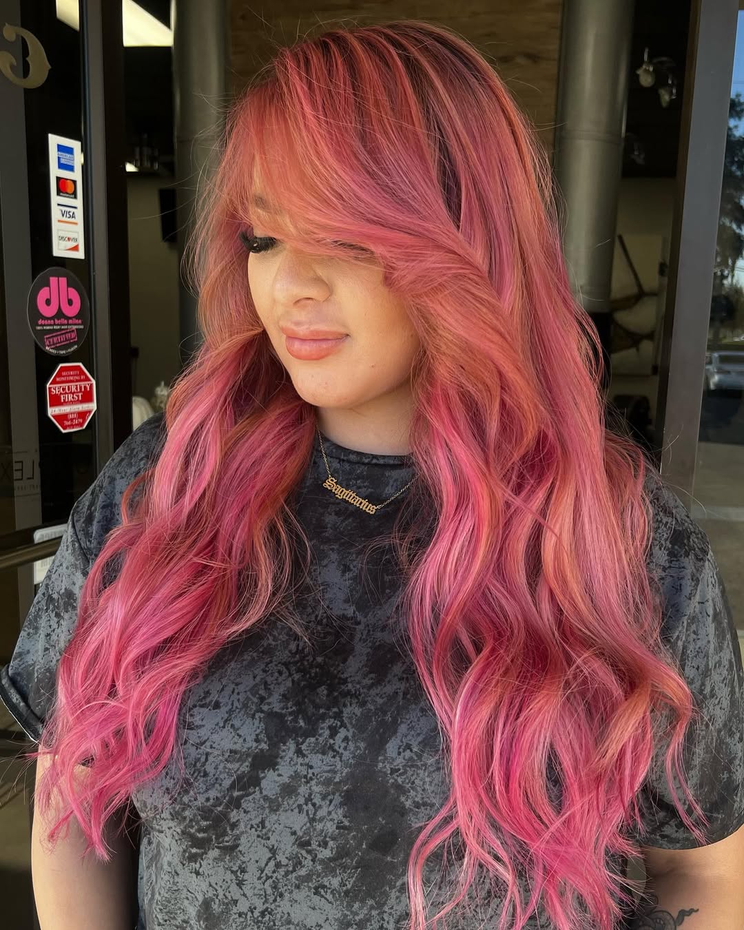 Woman with soft summer hair color 2026, light brown with subtle blonde highlights, wearing a casual denim jacket and a white t-shirt, smiling outdoors.
