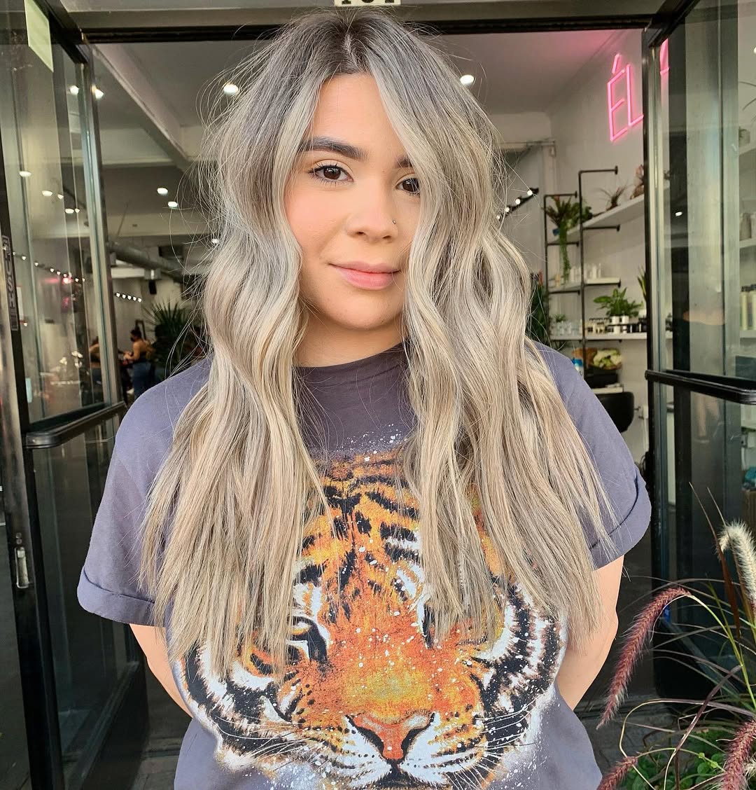Close-up of a woman with healthy, shiny soft summer hair color 2026. Her balayage features cool-toned brown roots blending into ash blonde highlights, framing her face beautifully.