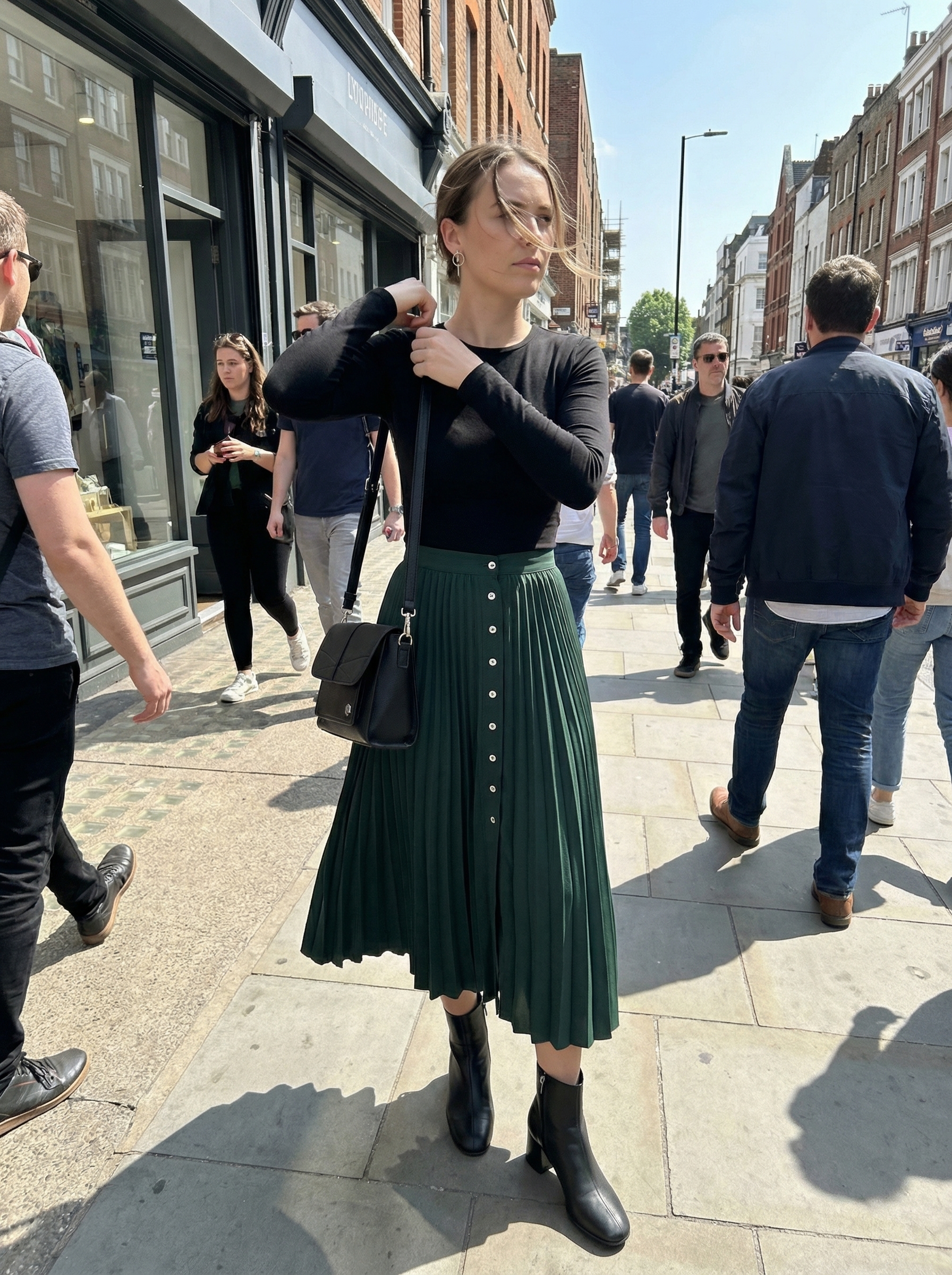 An artistic and polished 'Art Gallery Chic' look for spring summer outfits, featuring an olive green A-line midi skirt, black fitted long-sleeve top, leather ankle boots, and silver geometric earrings.