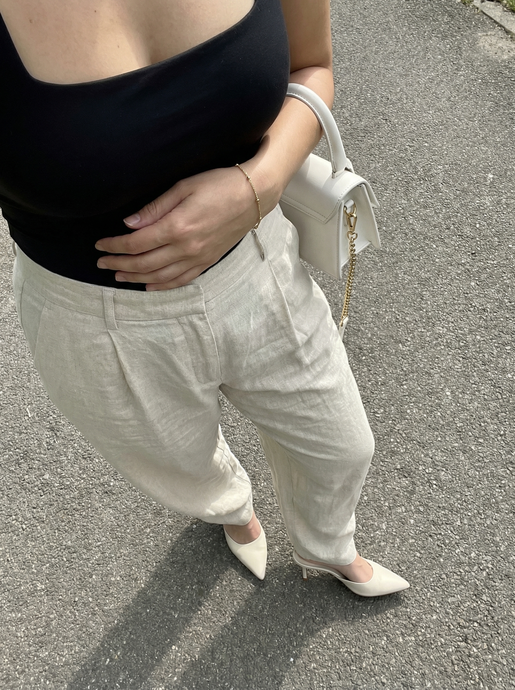 A sophisticated summer athleisure outfit 2026 with cream wide-leg trousers, a black square-neck bodysuit, and leather mules, suitable for a casual office.