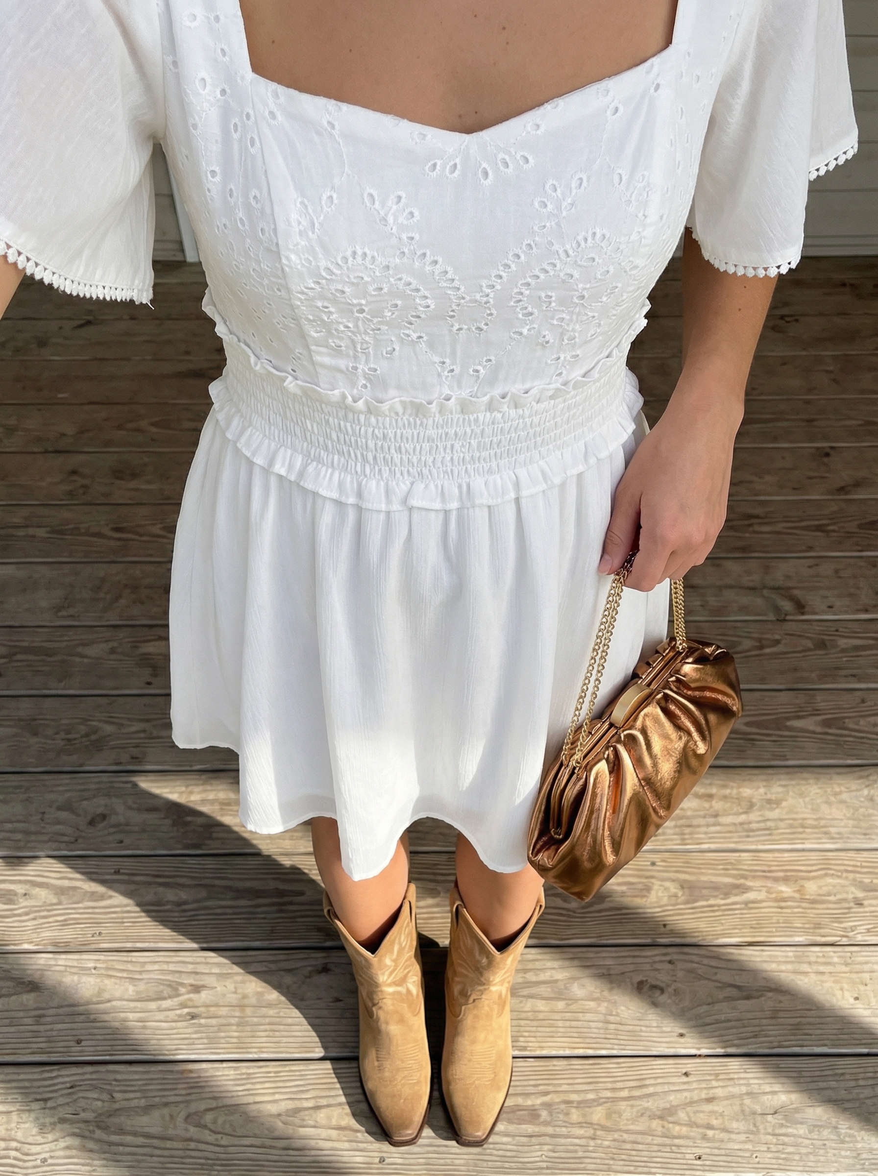 Summer Cowgirl Outfits 2024: Romantic Ranch Style A romantic summer cowgirl outfit featuring light beige suede cowboy boots, a white eyelet lace mini dress, and delicate pearl hoop earrings, perfect for a bridal shower.