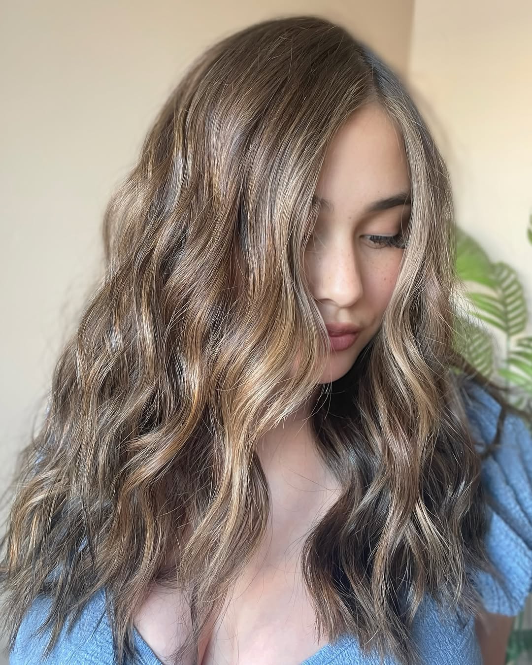 Model with long, sun-kissed blonde hair styled in loose beachy waves, perfect for summer hair ideas 2026. Her hair has subtle highlights suggesting effortless elegance for vacation or casual outings.