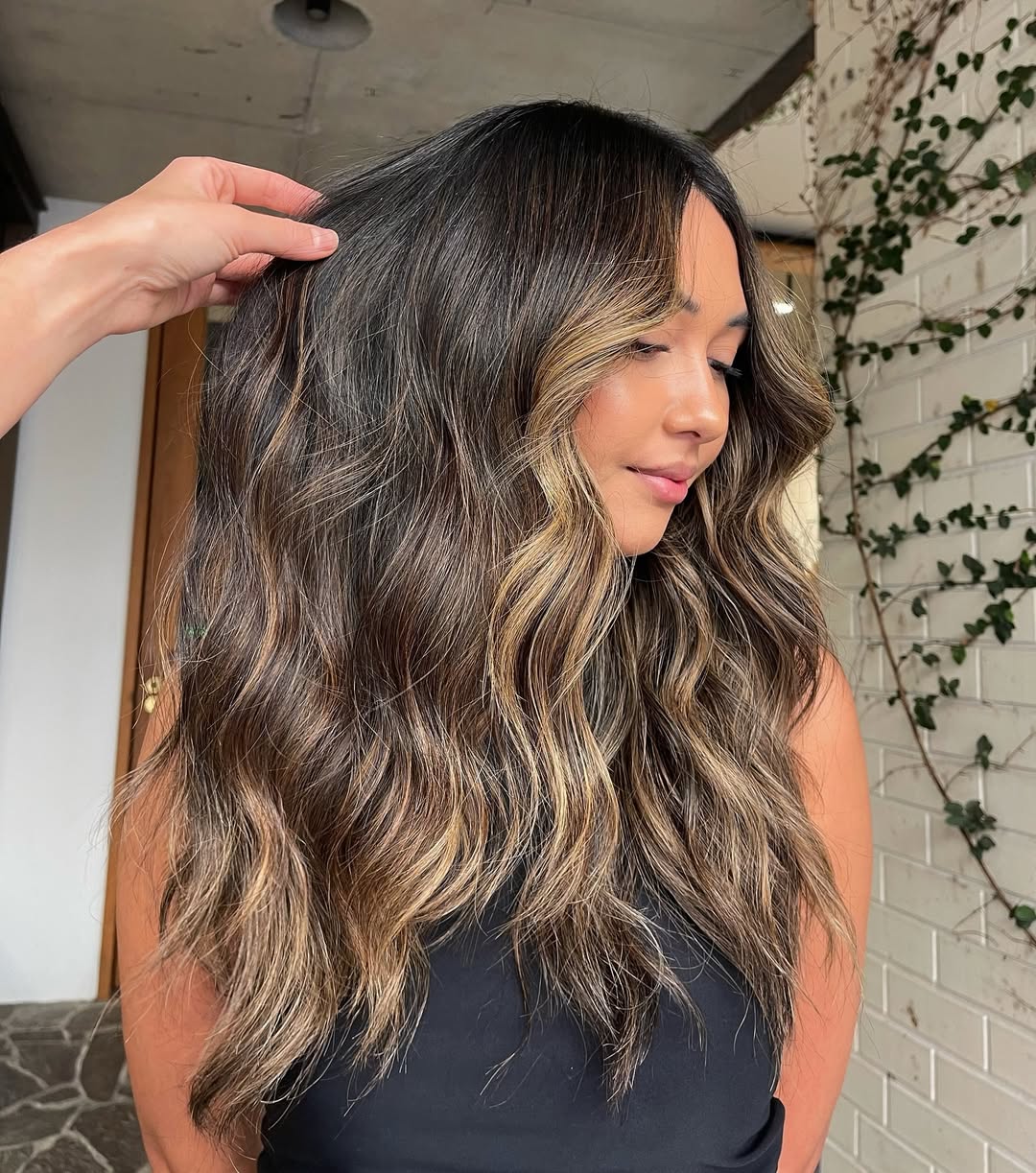 Blonde woman with long, shiny hair styled in soft, natural waves, perfect for summer hair ideas 2026. Her hair is parted in the middle, flowing over her shoulders.