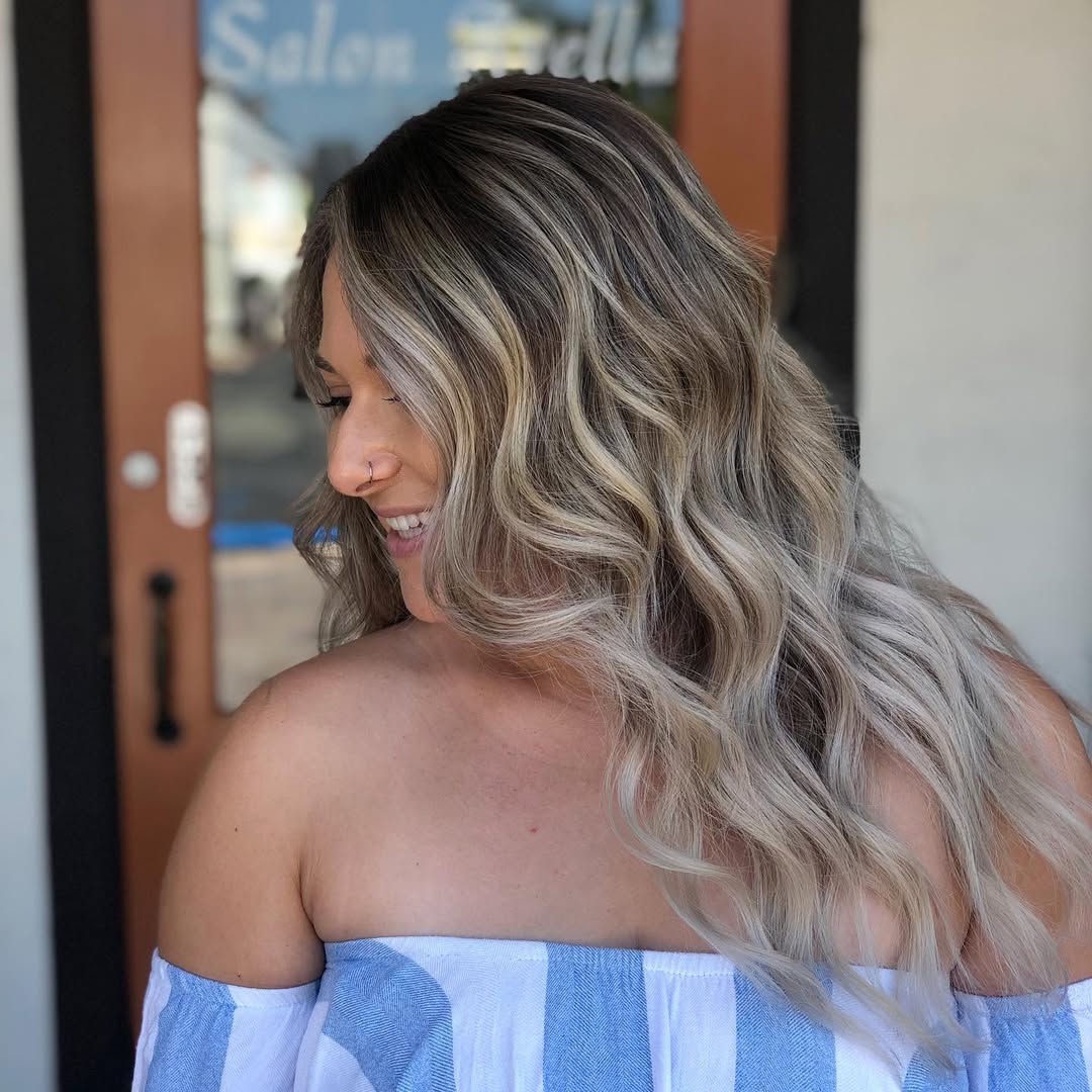 Beautiful woman with long, sun-kissed blonde hair styled in soft waves perfect for summer hair ideas 2026.