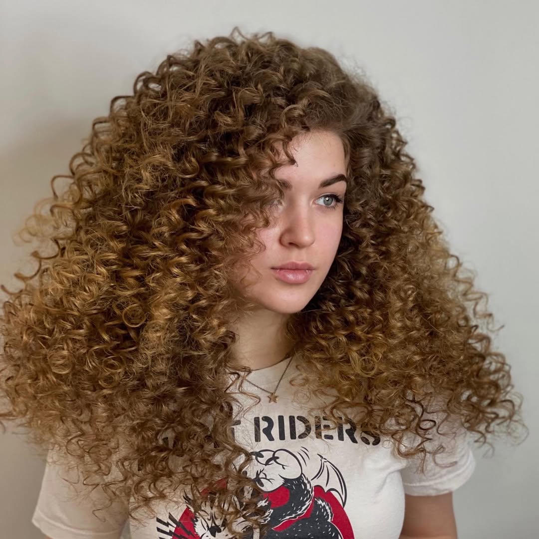 A woman confidently sports a sleek, high ponytail with a loose, wavy texture, perfect for sophisticated summer hairstyles 2026. She wears a chic white off-the-shoulder top.