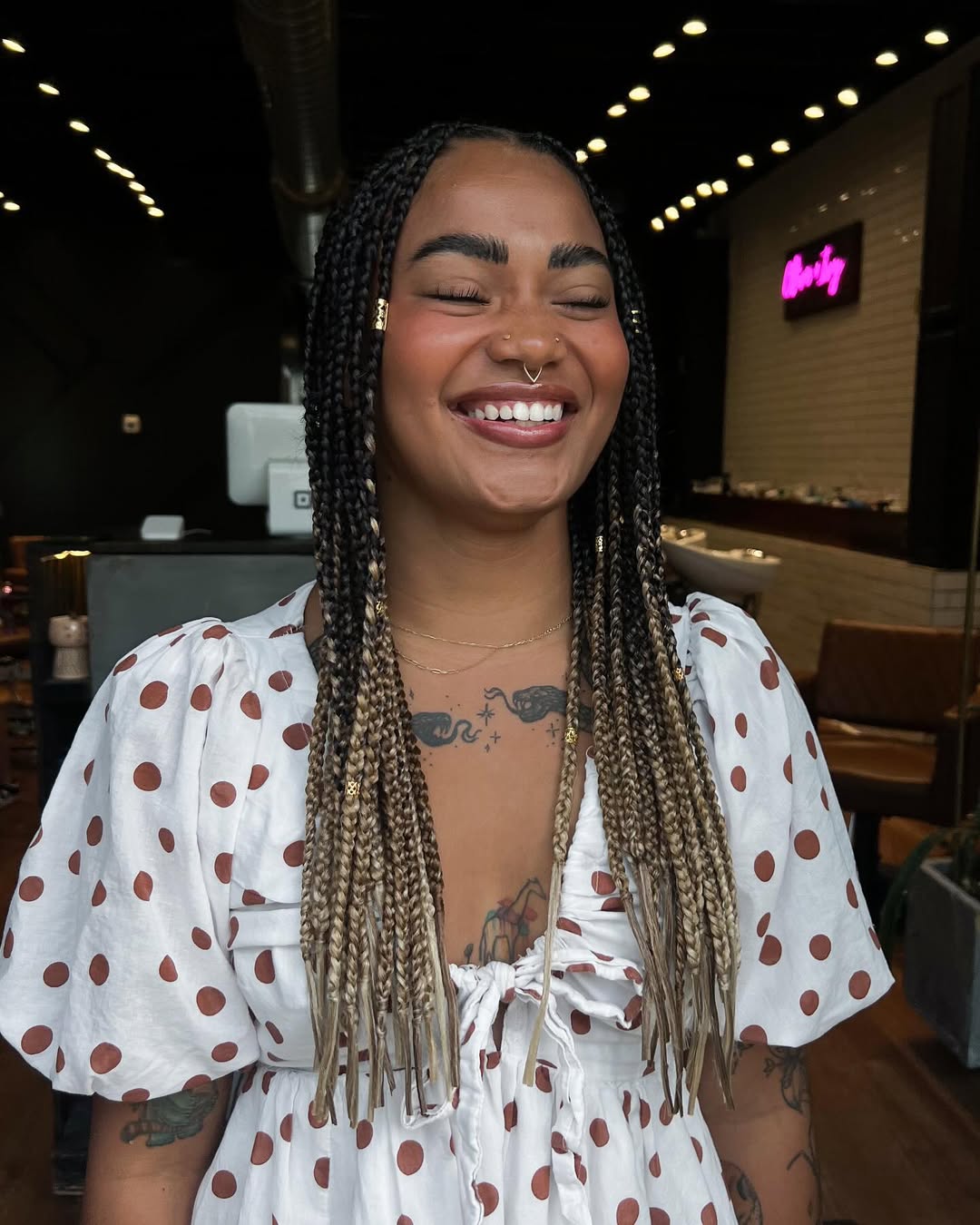 Close-up of a woman with intricate blonde box braids, styled into a high half-up bun, showcasing a chic summer hairstyle with braids for 2026.