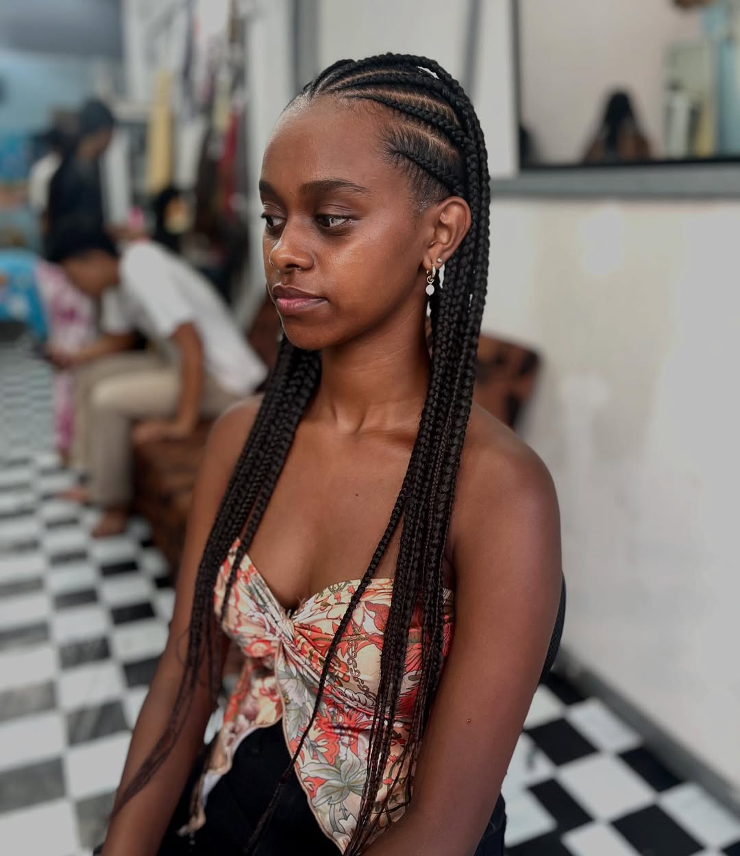 Close-up of a woman with long, dark hair styled in intricate cornrows with a side part, showcasing stylish summer hairstyles braids 2026. Perfect for a chic everyday look.