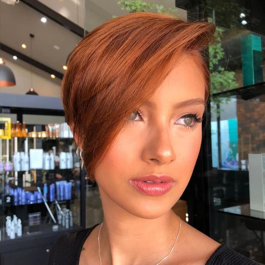 A woman with a chic, messy bun, showcasing a perfect example of summer hairstyles for short hair. Her dark hair is styled effortlessly for a casual sunny day look.