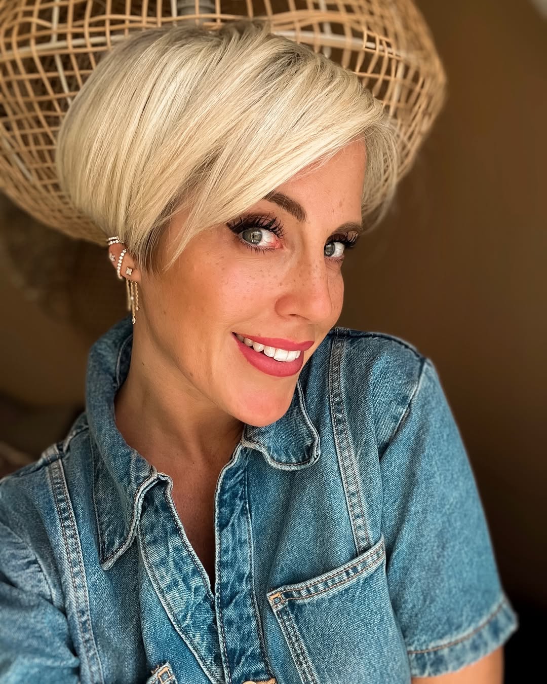 Close-up of a woman with a chic textured pixie cut, perfect for summer hairstyles for short hair. Her light brown hair has subtle highlights, styled with volume and a soft, wispy fringe that frames her face beautifully for a casual everyday look.