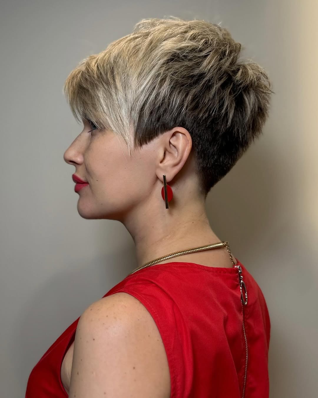Close-up of a woman with a playful, textured pixie cut, perfect for casual summer hairstyles for short hair. Her short, light brown hair is styled with soft waves and bangs framing her face, ideal for warm weather.