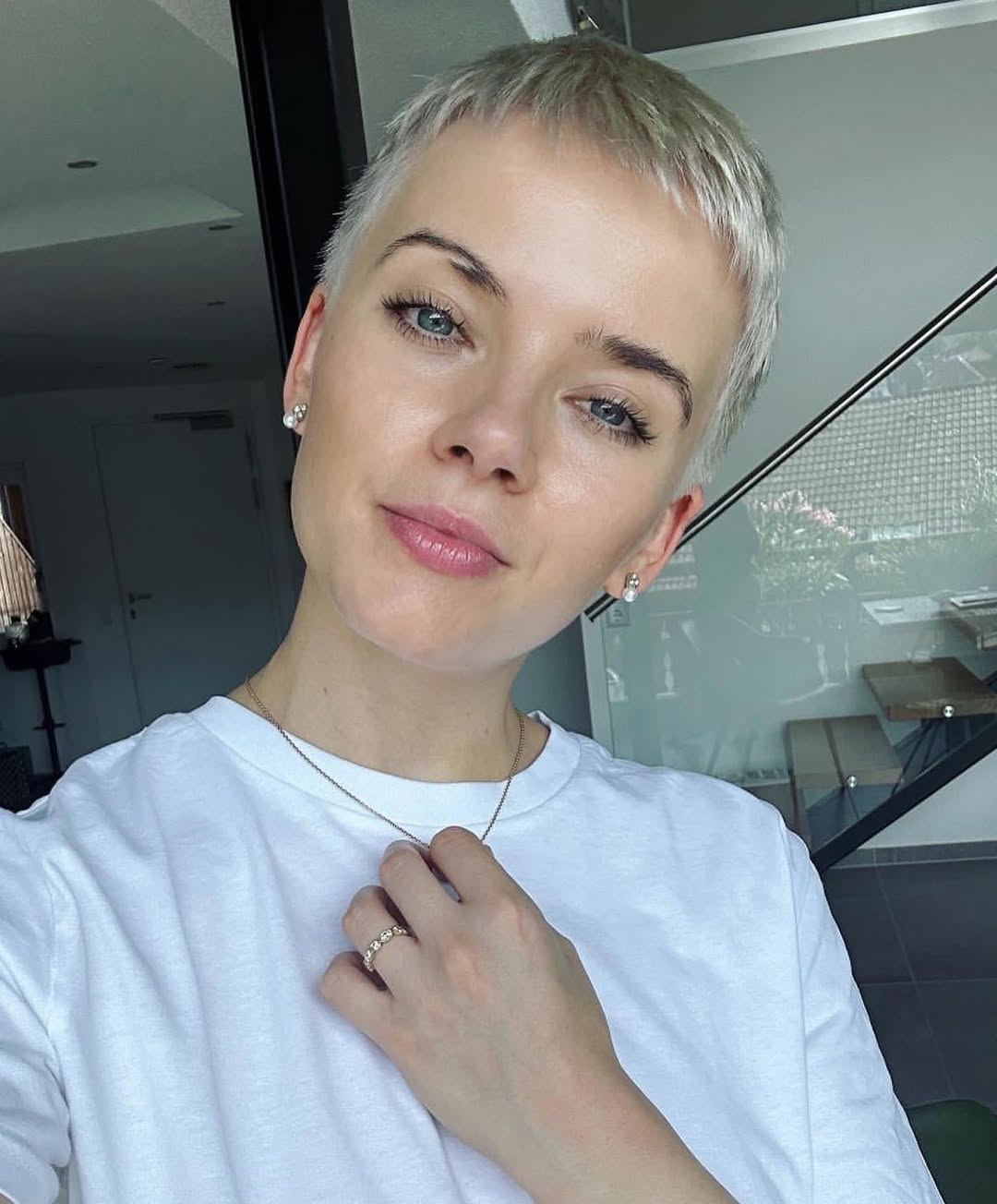 A woman with a chic pixie cut, showcasing a refreshing summer hairstyle for short hair. The outfit features a vibrant yellow floral sundress with delicate ruffles, perfect for a casual sunny day outdoor event or brunch.