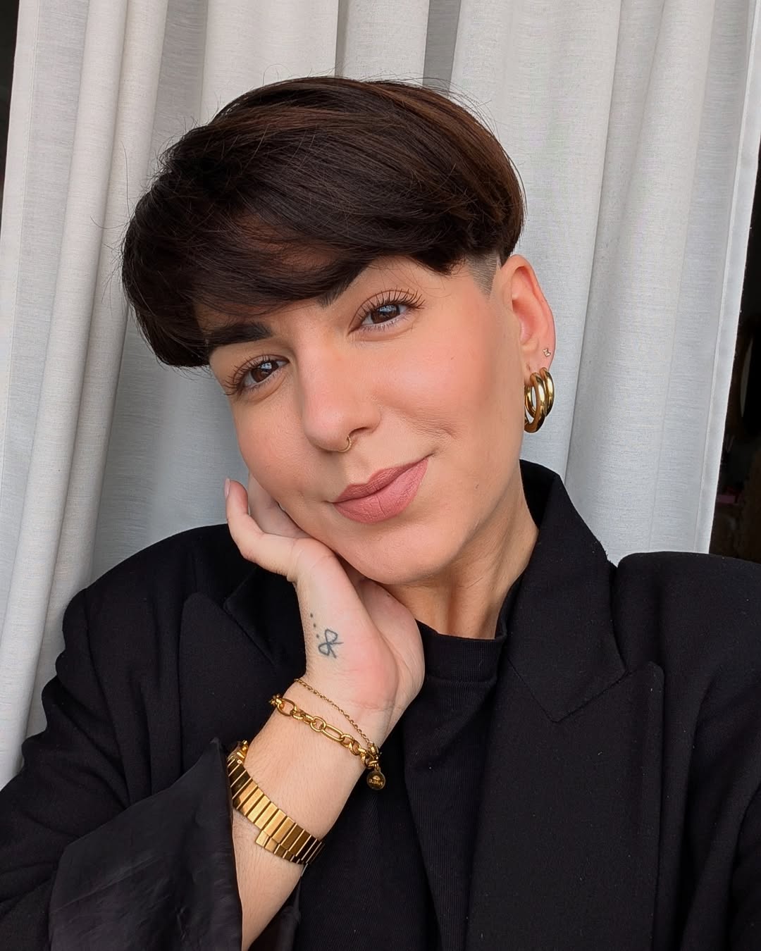 A stylish woman with a chic pixie cut, showcasing perfect summer hairstyles for short hair, wearing a white casual top in a bright outdoor setting.