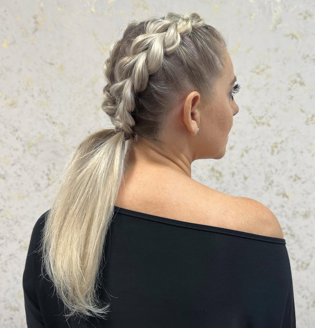 A woman with a chic, messy, low-braided bun, perfect for summer hairstyles for long hair 2026. Her dark hair is casually styled, ideal for a warm day.