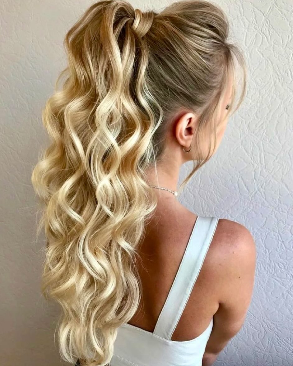 Woman with long, wavy blonde hair styled in a half-up twist, perfect for summer hairstyles for long hair 2026. She wears a floral maxi dress, ideal for a garden party or casual summer outing.