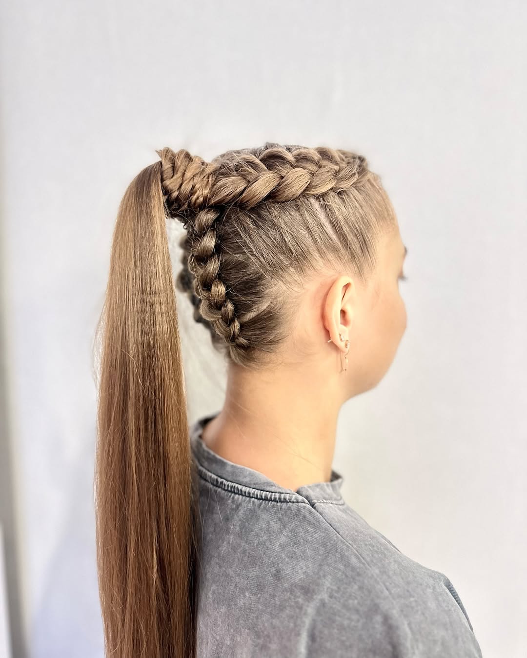 Beautiful woman with long blonde hair styled in a chic, voluminous half-up waves, perfect as an elegant summer hairstyle for long hair 2026. She wears a white top and subtle earrings.