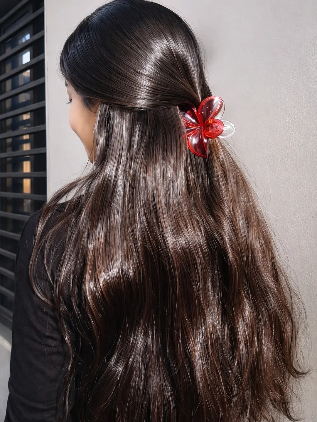 Blonde woman with long, sun-kissed hair in a relaxed messy bun, perfect for summer hairstyles for long hair 2026. She wears a white tank top and gold hoops.