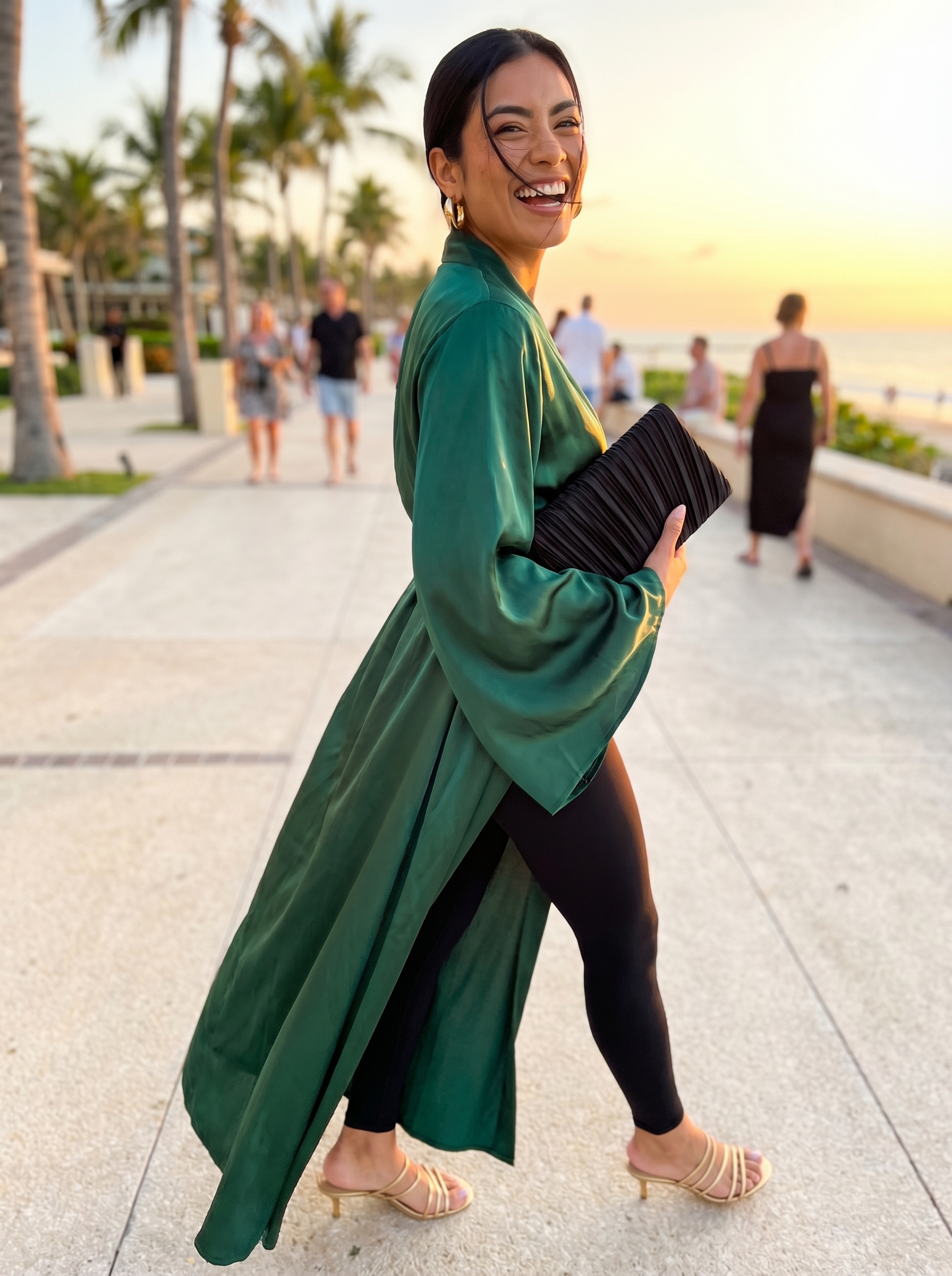 Luxurious resort-ready summer leggings outfit featuring black seamless high-waisted leggings, an emerald green silk blend kimono top, gold hoop earrings, and black heeled slide sandals. Perfect for upscale resort wear or vacation dinners. Discover stylish summer leggings outfits 2026 ideas.
