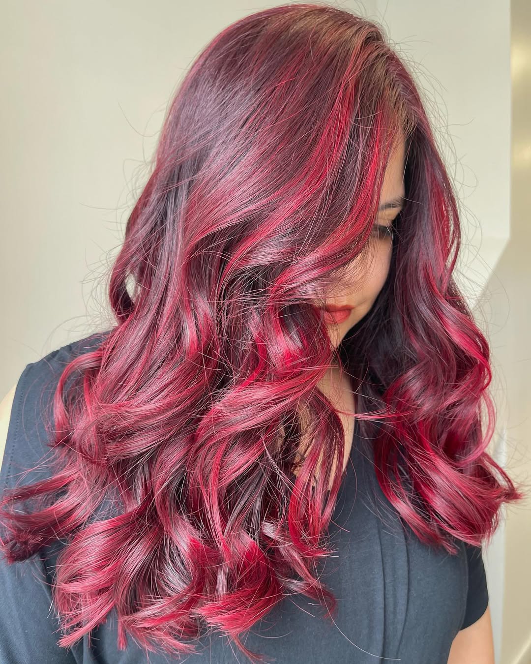 Beautiful woman with vibrant summer red hair color 2026, styled in soft waves, wearing a floral sundress for a casual summer day.
