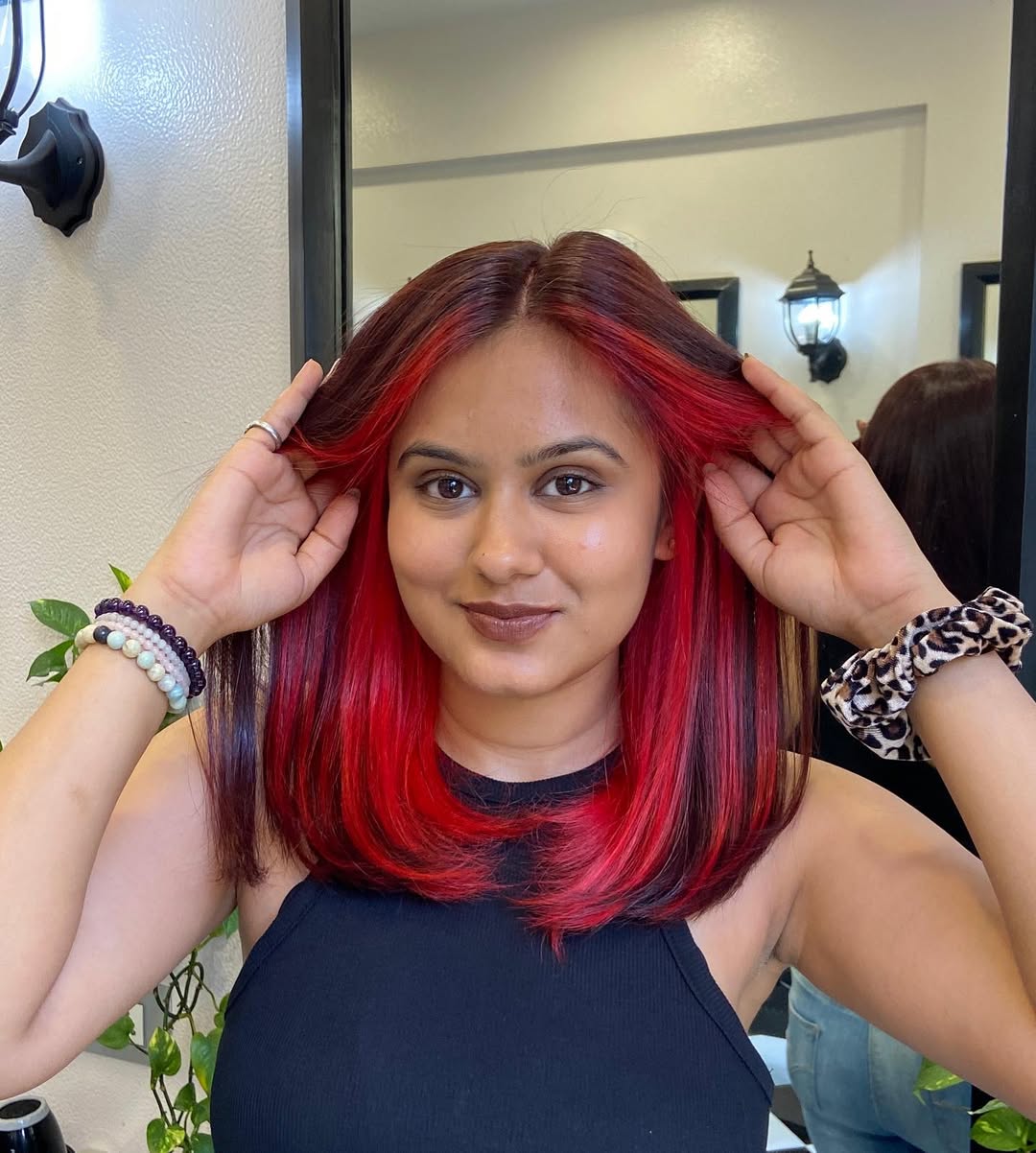 A woman with vibrant summer red hair color 2026, styled in loose waves, wearing a chic white linen dress for a casual summer day.