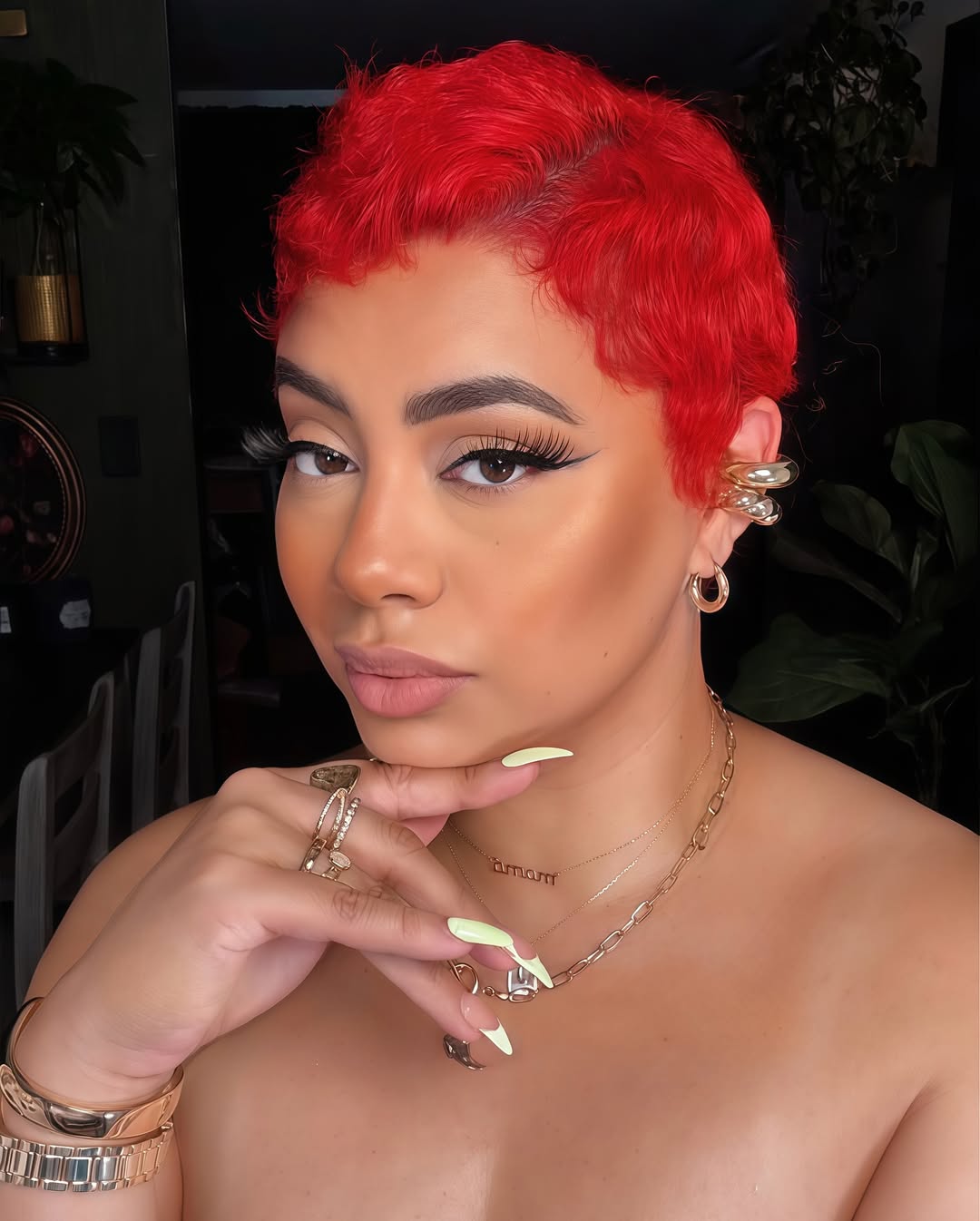 A woman with vibrant summer red hair color 2026 smiles, wearing a chic white linen button-down shirt and light blue denim shorts, perfect for a sunny day.