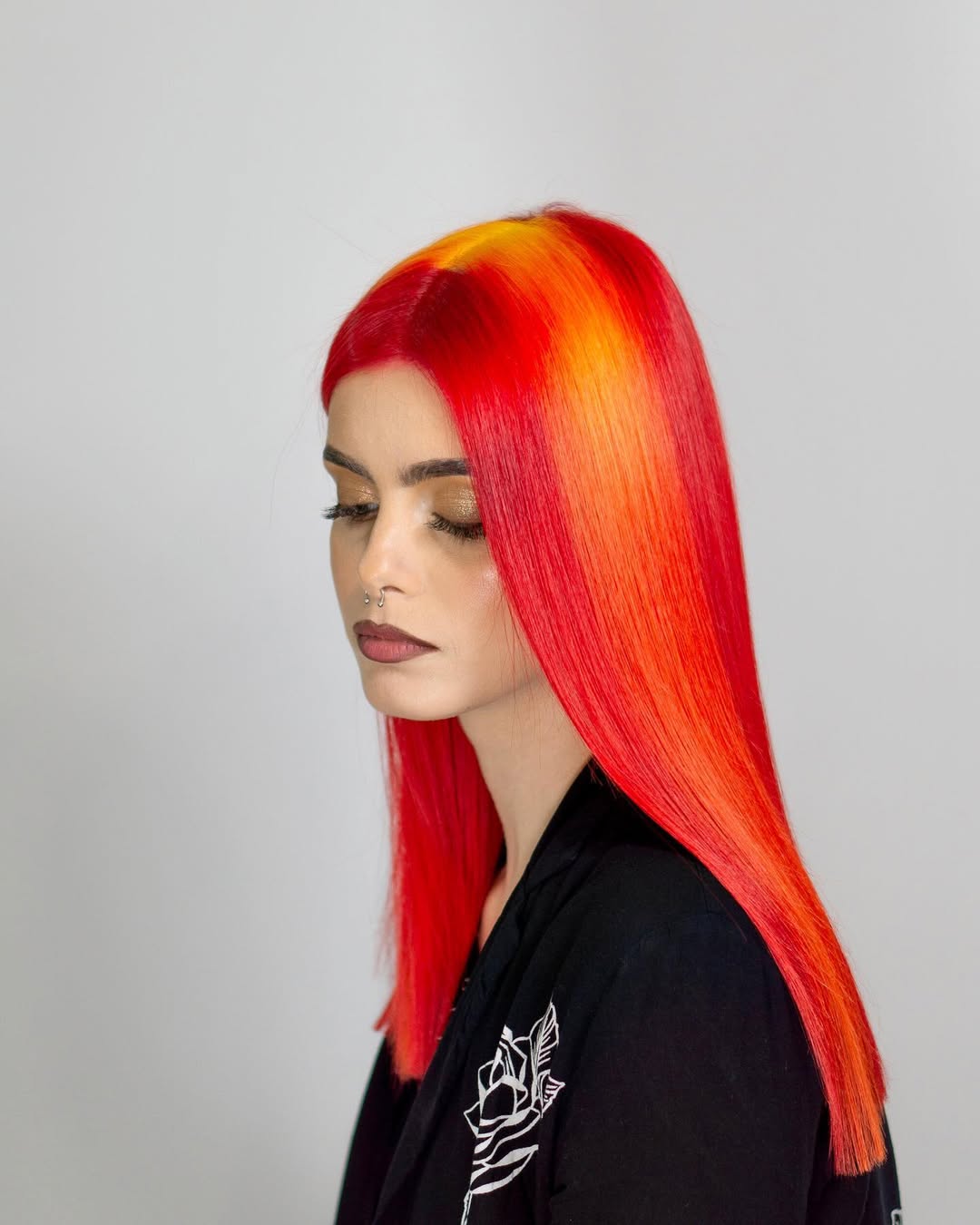 A woman with vibrant summer red hair color 2026, styled in loose waves, wearing a chic white linen dress at a beach resort.