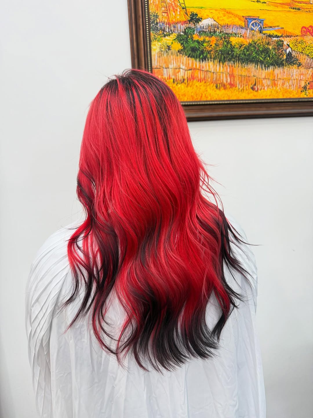 Beautiful woman smiling with a vibrant summer red hair color 2026, styling her rich auburn curls for a sunny outdoor event.