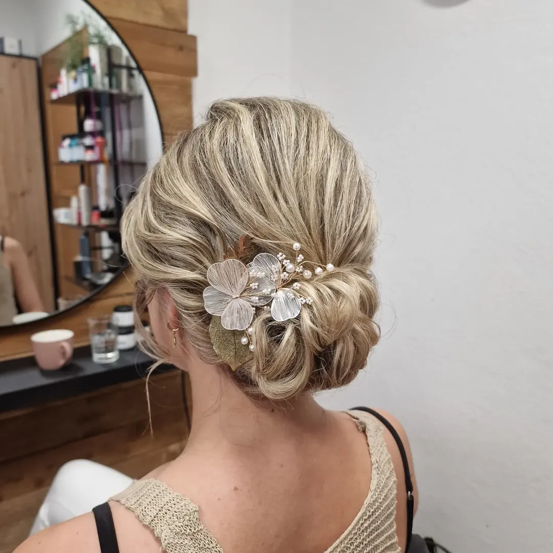 Elegant brunette woman with a chic updo, perfect for summer wedding guest hair 2026. Her hair is styled in soft waves pinned back, showcasing a delicate neckline. Ideal for a formal or semi-formal summer event.