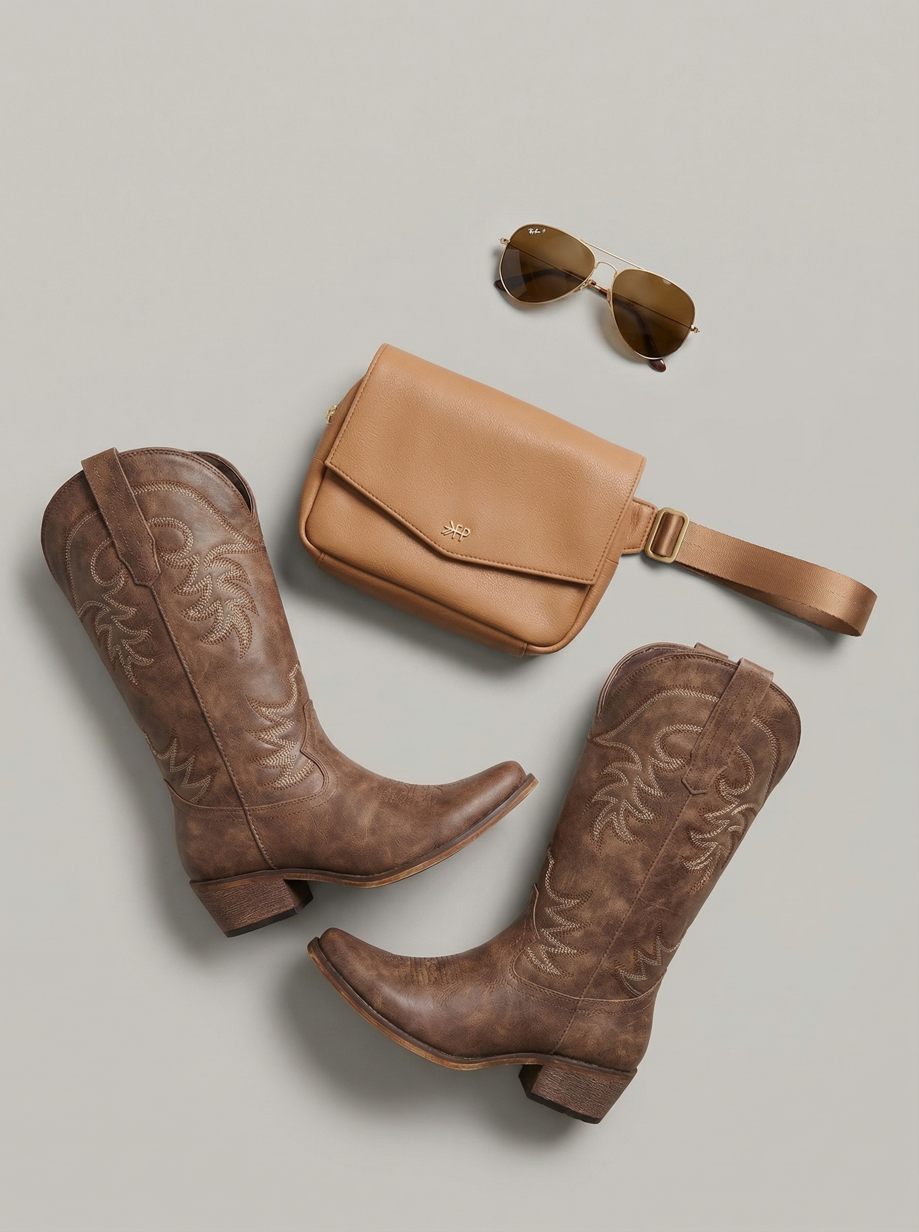 A woman wears a western chic olive green utility jumpsuit with tan cowboy boots, a red bandana, and aviator sunglasses for a stylish day trip look.