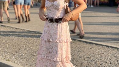 Feminine western summer outfit 2026: a dusty rose floral maxi dress, classic cowboy boots, a structured saddle bag, and a wide western belt for an outdoor concert.