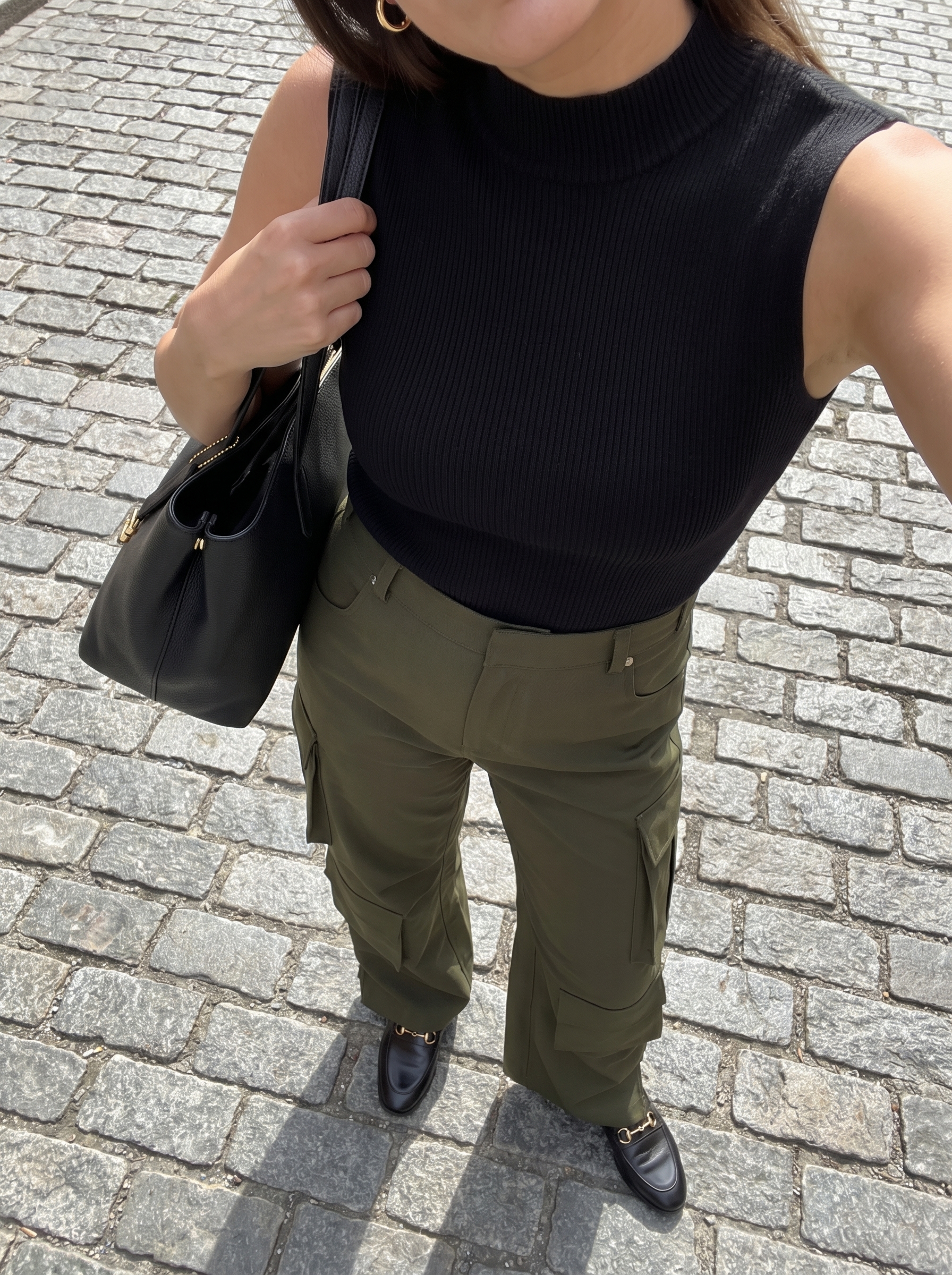 Polished olive green cargo pants and a black mock neck top create modern western summer outfits for brunch. Black loafers and gold hoops add sleek details.