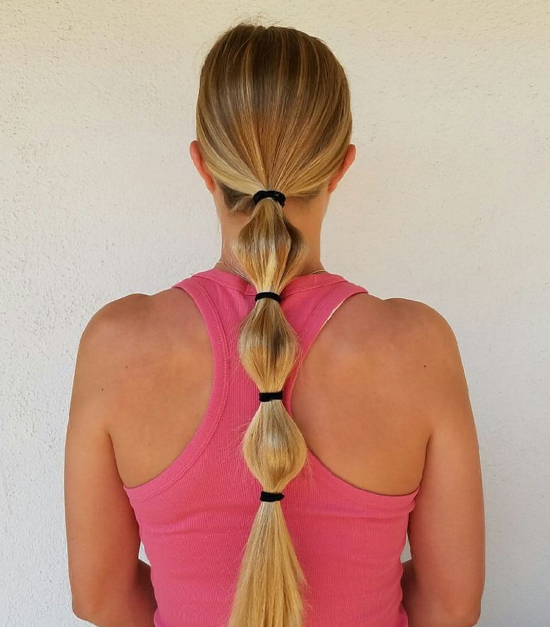 Blonde woman with a chic, high messy bun, perfect for various hairstyles for hot weather 2026. This casual updo features loose strands framing her face, ideal for summer days.