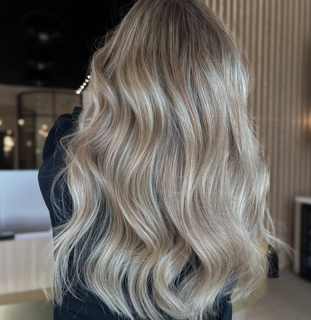 Close-up of a woman showcasing beautiful soft summer blonde hair 2026, styled in loose waves, paired with a subtle, natural makeup look. Perfect for a chic everyday aesthetic.