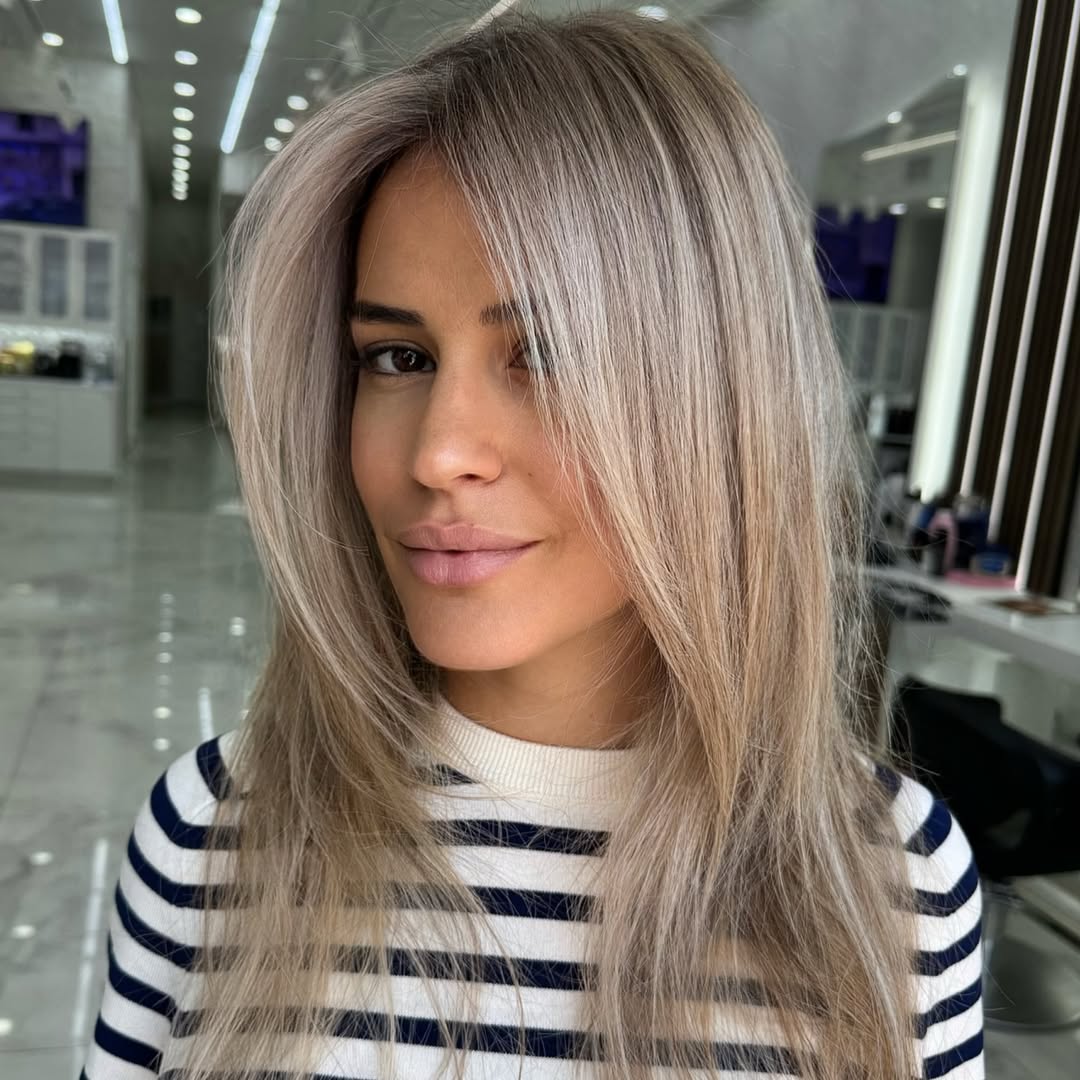 Woman with natural ash blonde soft summer hair ideas 2026, styled in loose, beachy waves, perfect for a casual sunny day.
