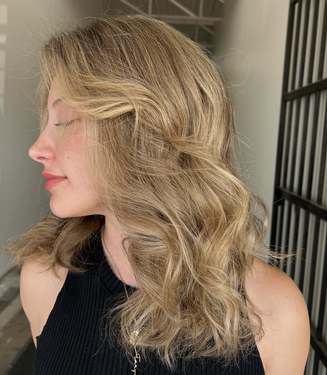 Woman with long, wavy blonde hair in a half-up style, showcasing soft summer hair ideas with delicate face-framing pieces for an elegant, effortless look.