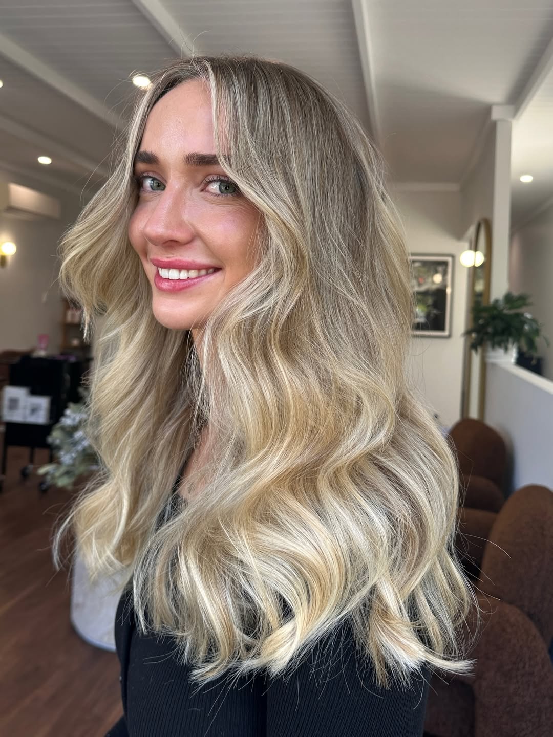 Close-up of a woman with natural, sun-kissed soft summer hair ideas 2026, featuring subtle blonde highlights framing her face, perfect for a casual daytime look.