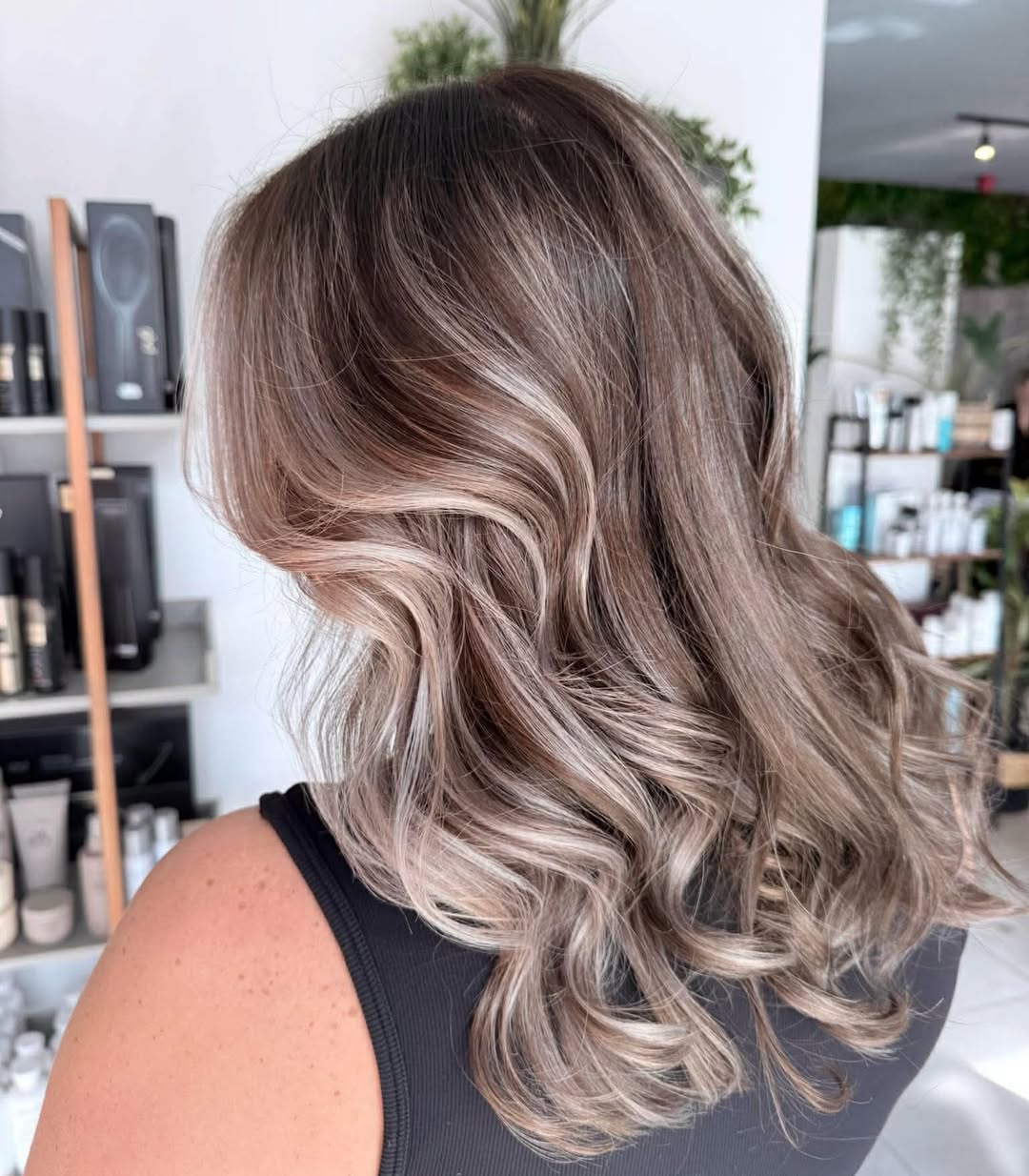 Close-up of a woman with long, sun-kissed blonde hair featuring soft summer waves, styled with a subtle side part and a natural, effortless flow, highlighting soft summer hair ideas.
