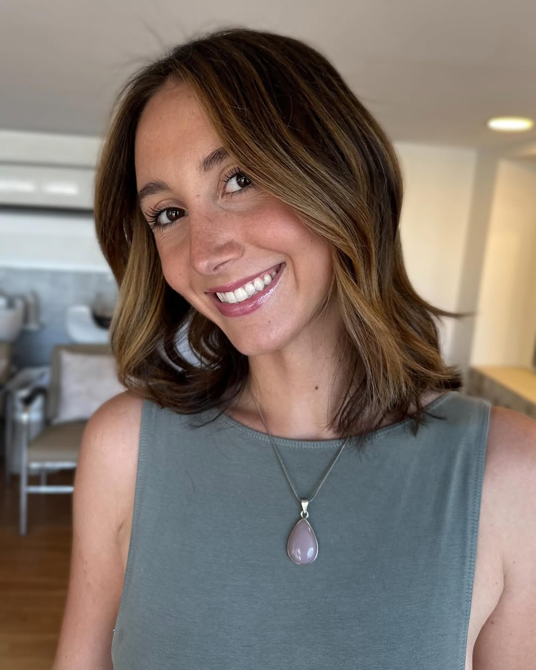 A woman with a soft, wavy brunette hairstyle, styled for soft summer hair ideas. Her hair gently frames her face, indicating a natural, effortless look. This style is perfect for a relaxed yet chic vibe.