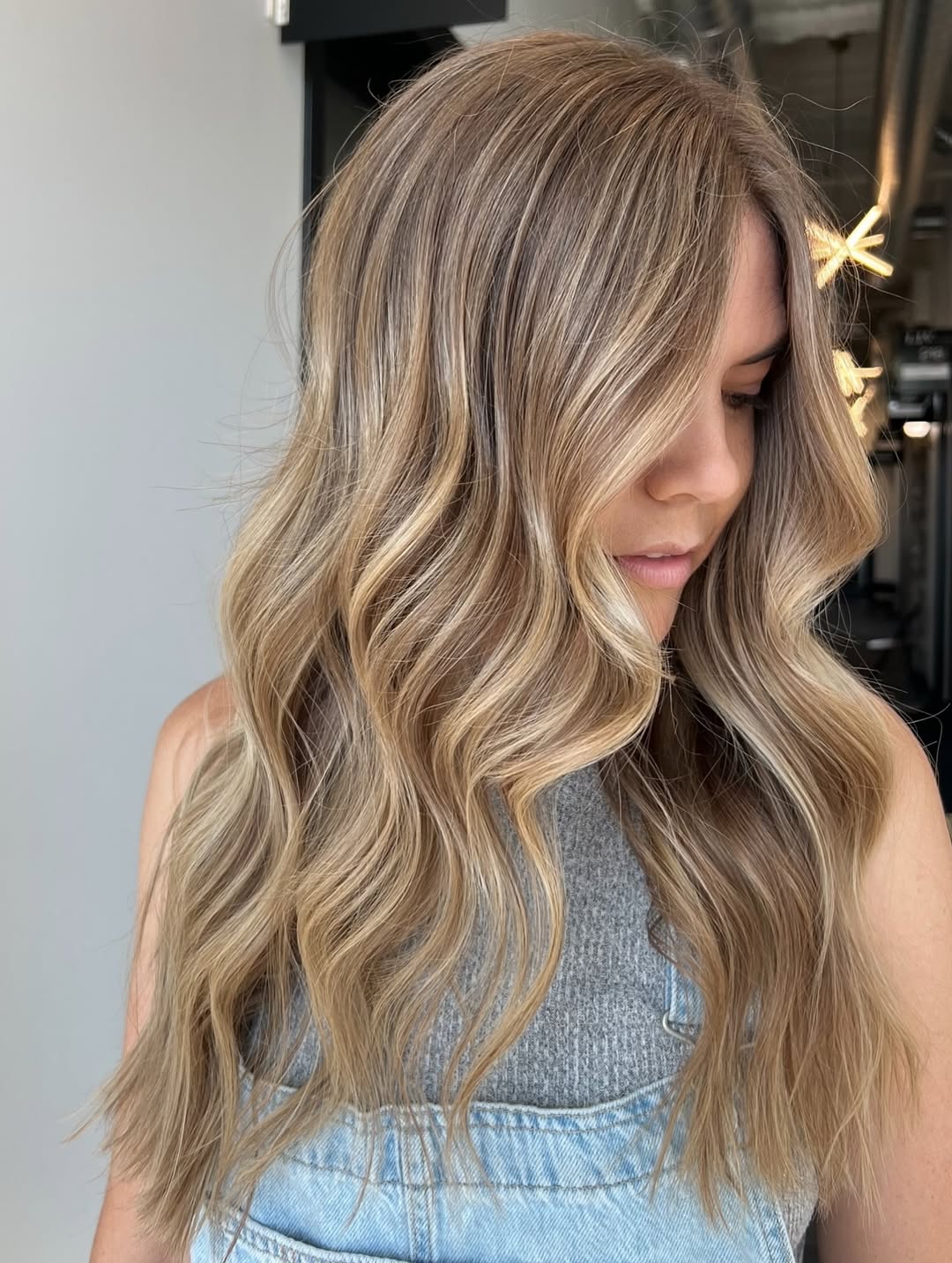 Close-up of a woman with natural waves, chestnut balayage, and face-framing highlights, showcasing chic soft summer hair ideas. Her hair is effortlessly styled, perfect for a relaxed yet polished look.