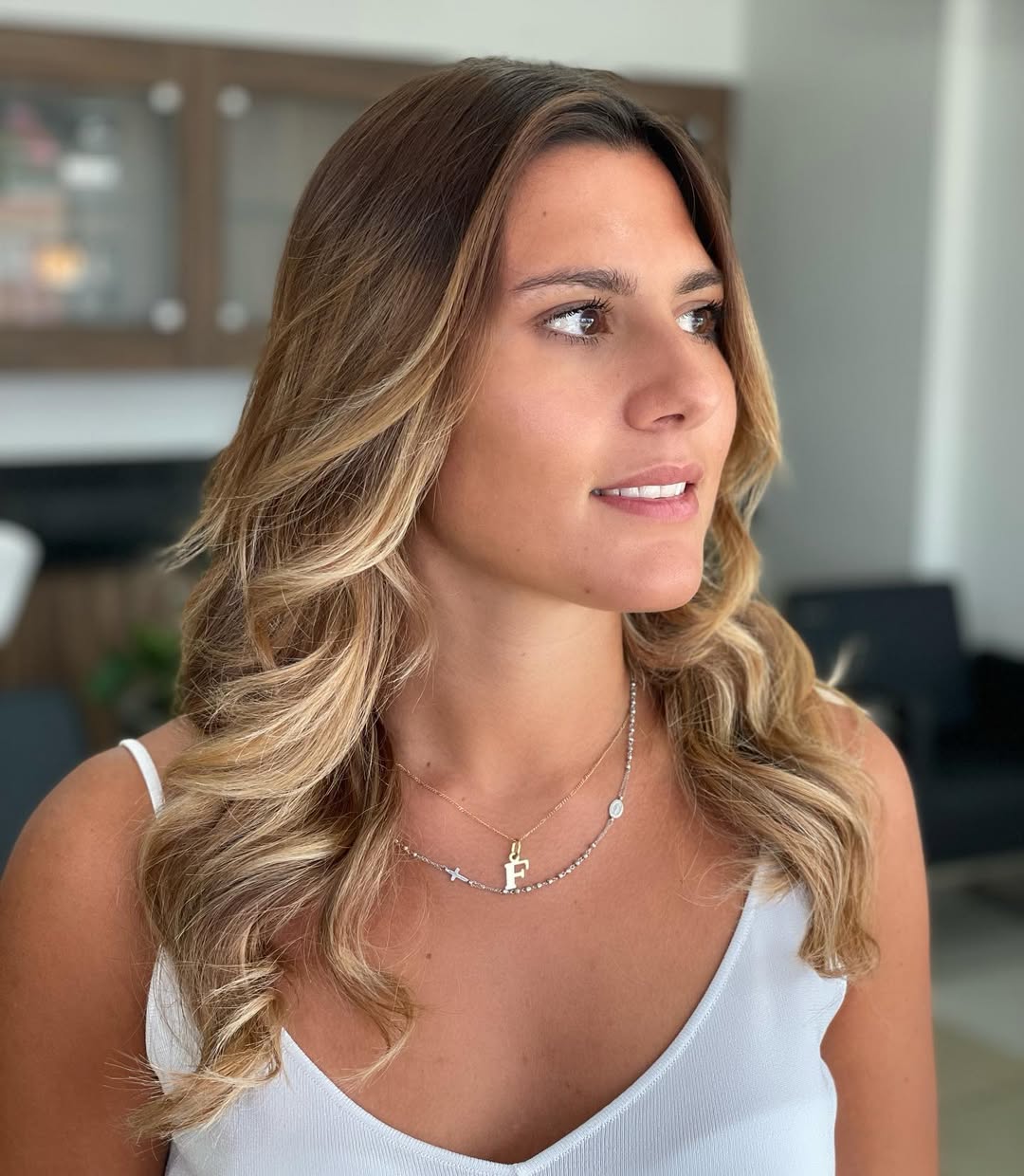 Close-up of a woman with long, sun-kissed blonde hair styled in loose beach waves, perfect summer beach hair ideas. Her hair has subtle highlights.